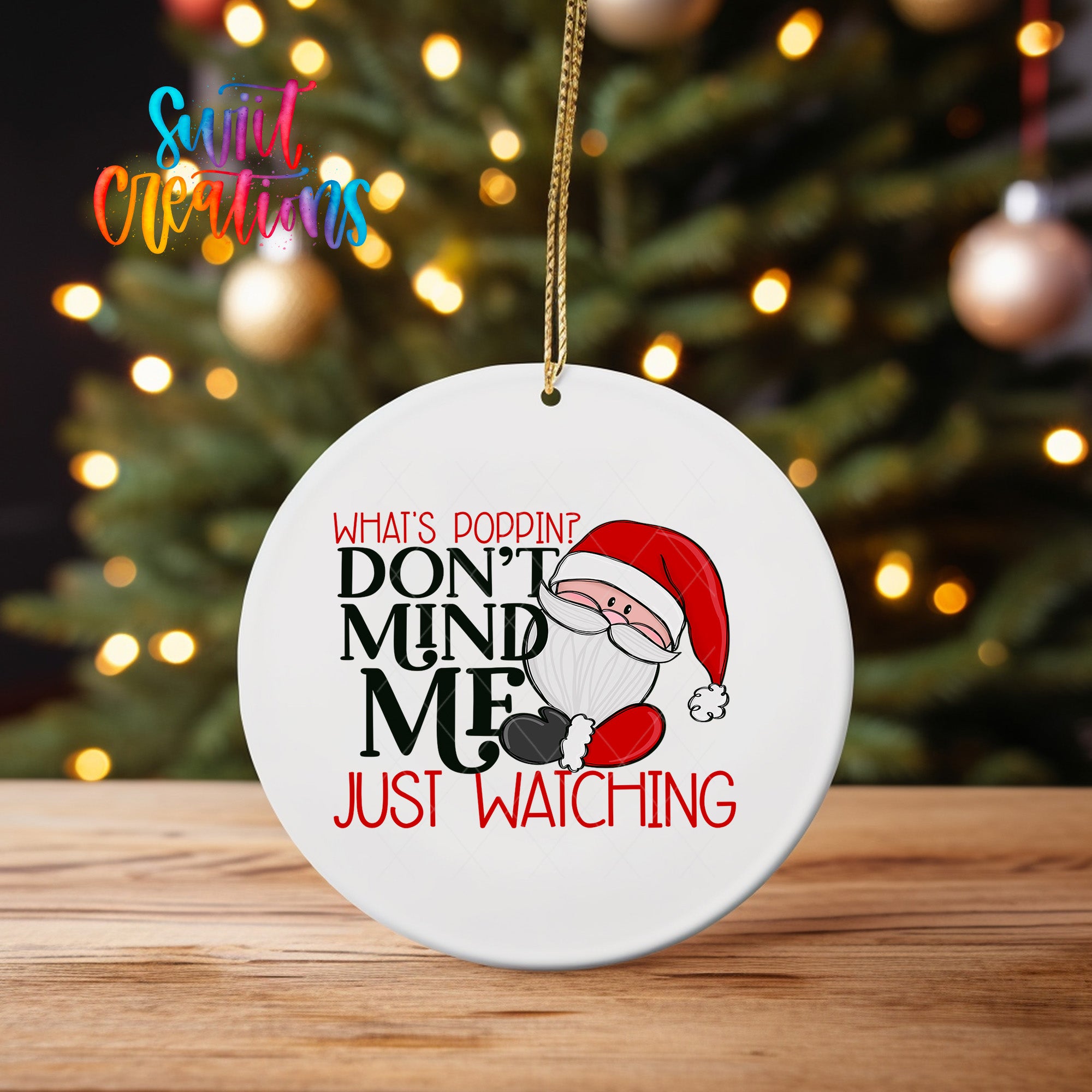 A white ornament with a Santa Claus design and text that reads "What's Poppin? Don't Mind Me Just Watching" hanging from a string.