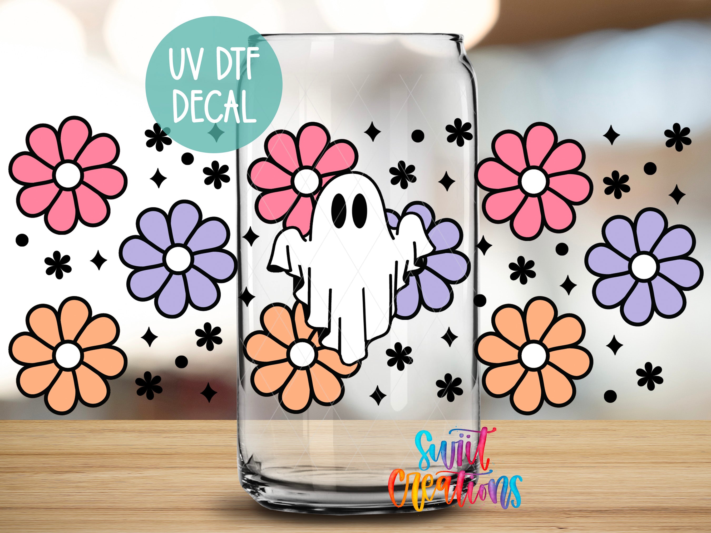 a glass jar with a ghost decoration and colorful flowers on a table.