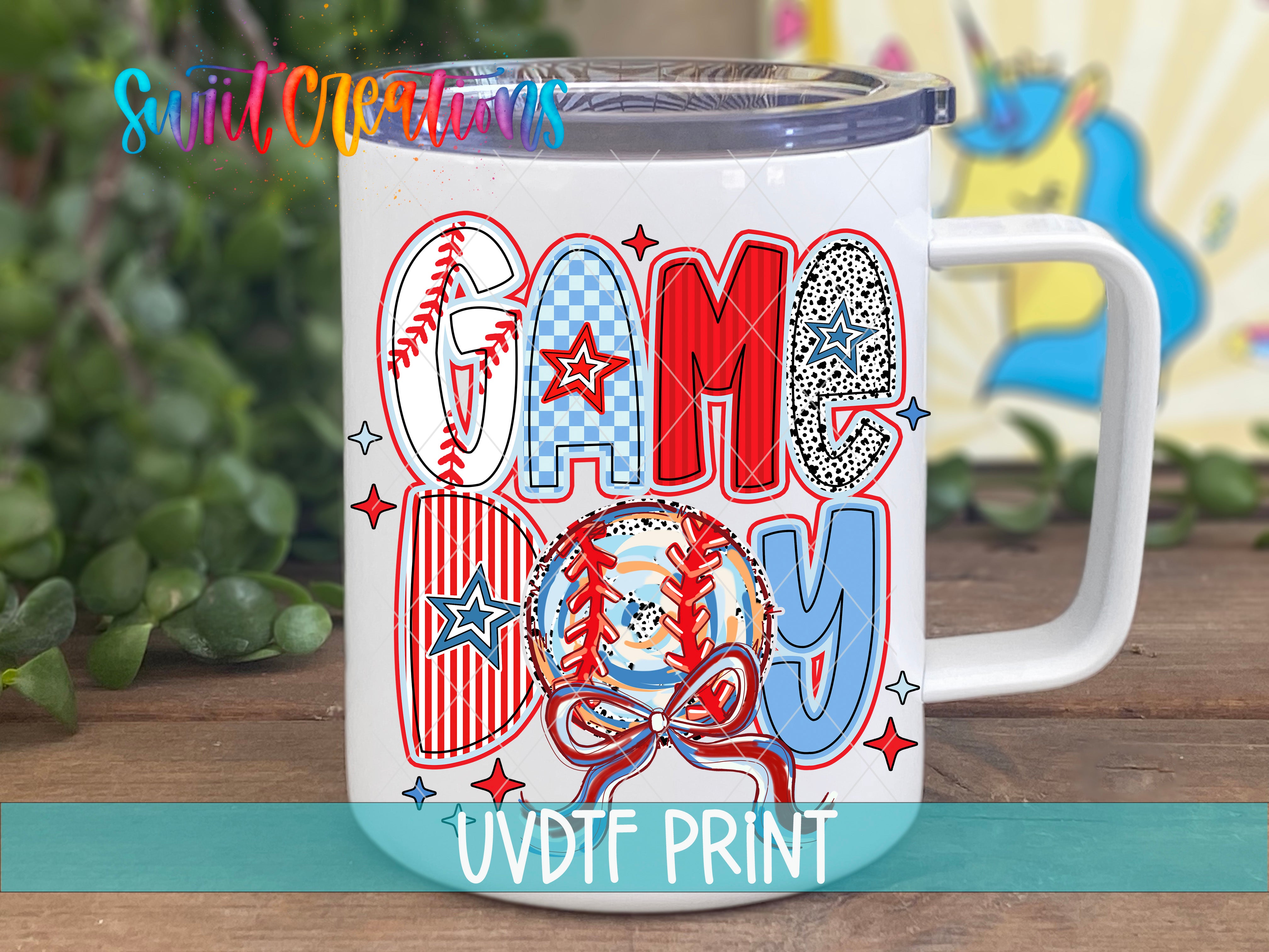 A white mug with a colorful design featuring the word "GAME DAY" and various sports-related elements such as baseballs, stars, and stripes.