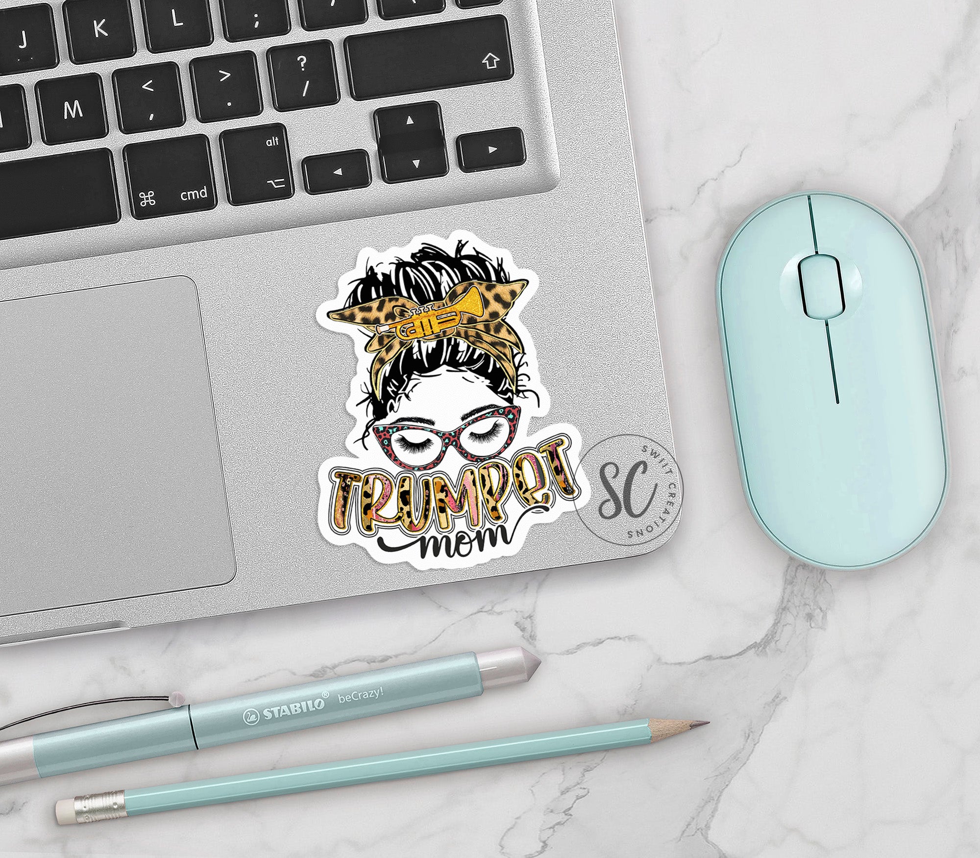 a laptop with a sticker of a woman's face next to a mouse