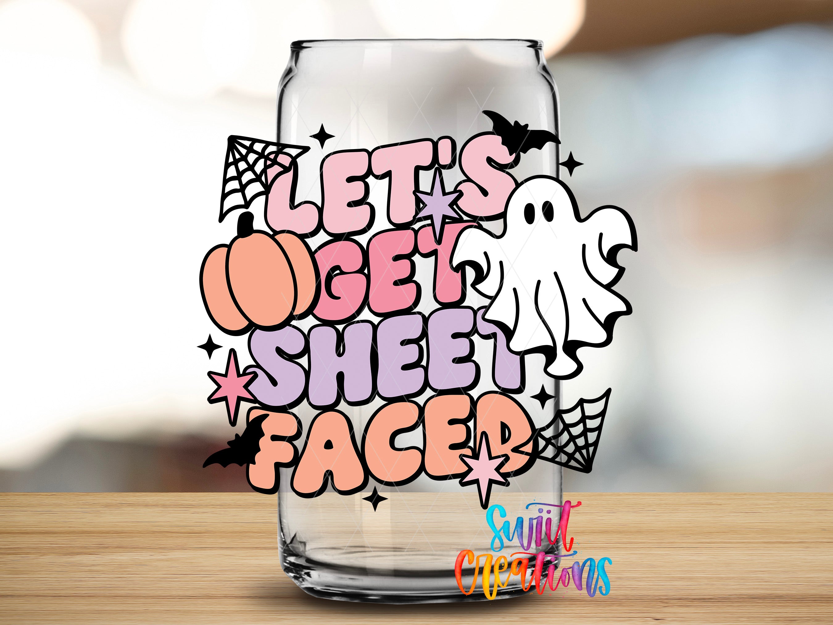 A glass with a Halloween-themed design on it, featuring a ghost, spider web, pumpkin, and the text "Let's get sheet faced".
