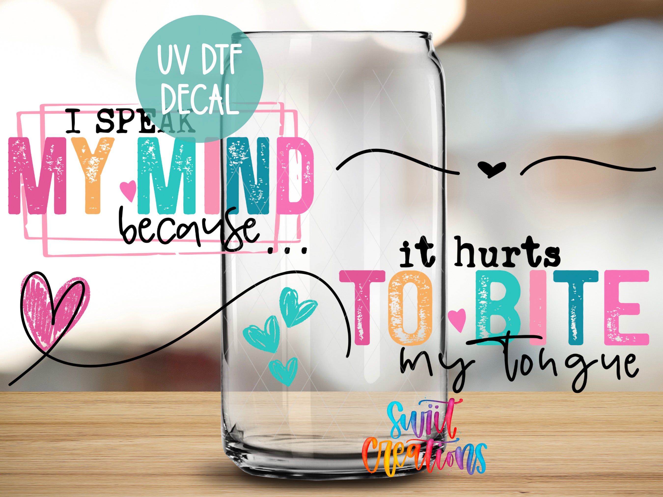 a clear glass with colorful text and drawings on it, placed on a wooden surface.