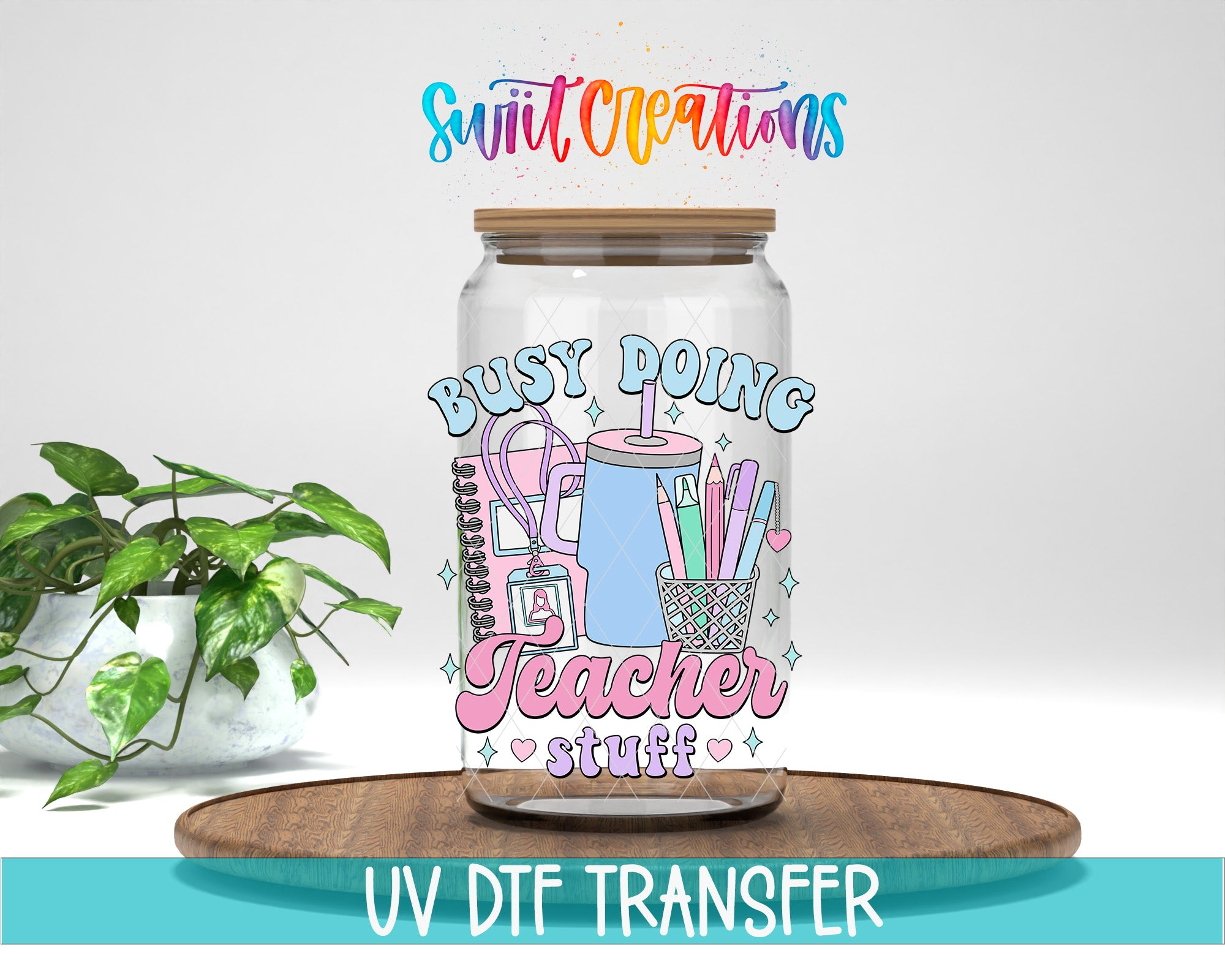 A glass jar with a colorful design and text, placed on a wooden surface next to a potted plant.