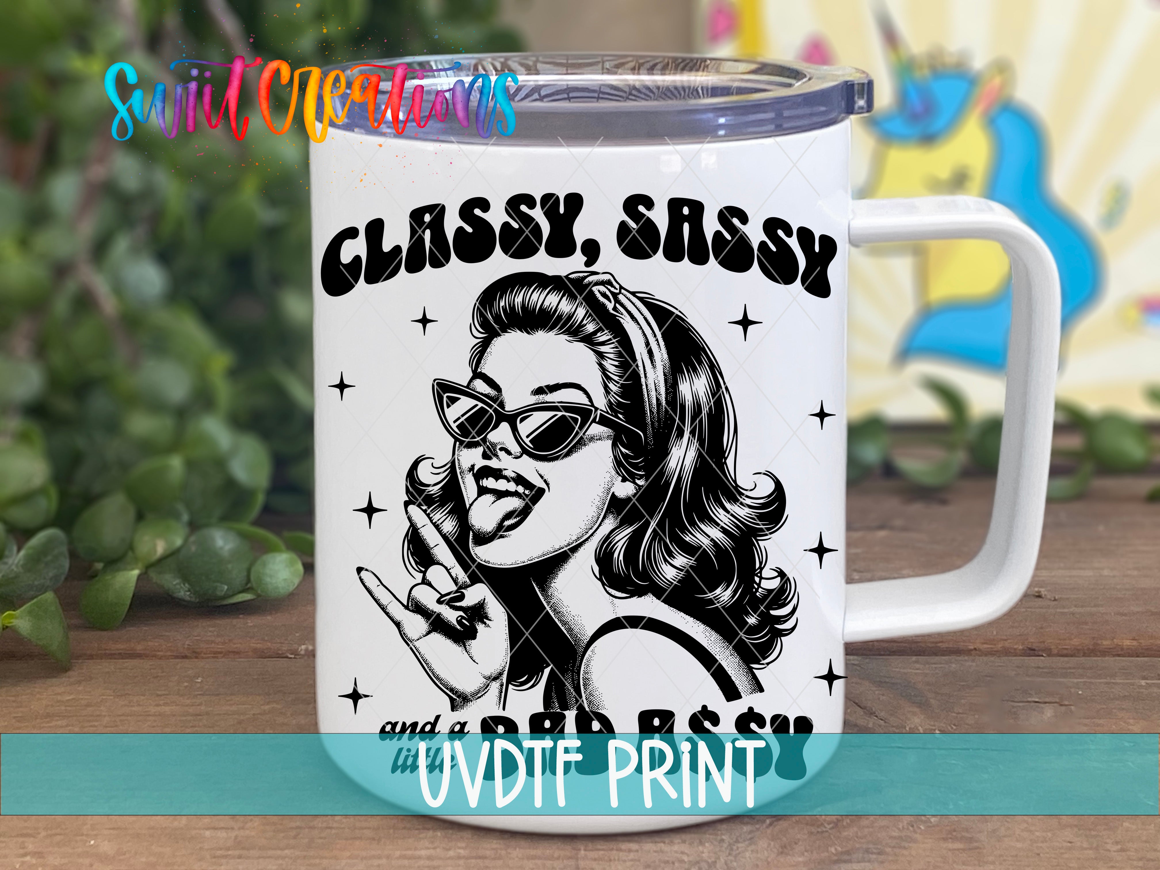 A white mug with a black and white illustration of a woman wearing sunglasses and a sassy expression, along with the text "CLASSY, SASSY and a BAD RASSY" printed on it.