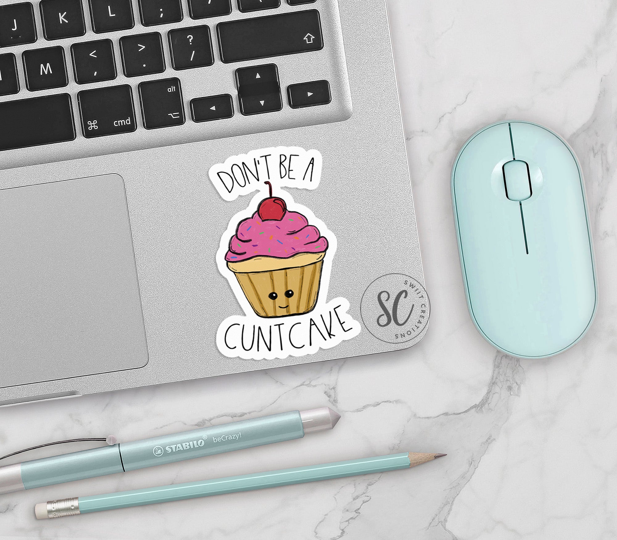 a cupcake sticker on a laptop next to a mouse