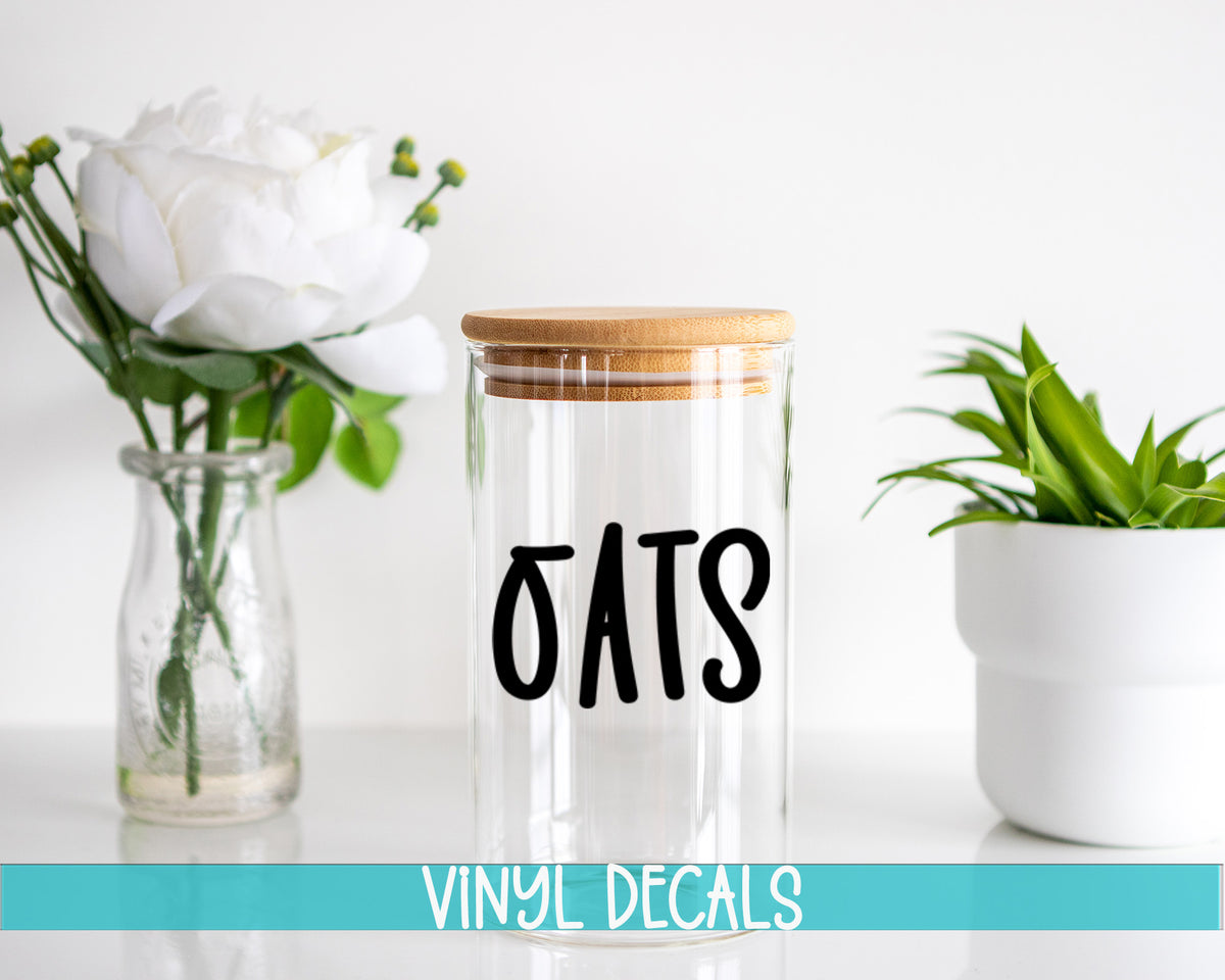a glass jar with a wooden lid sitting next to a vase with white flowers