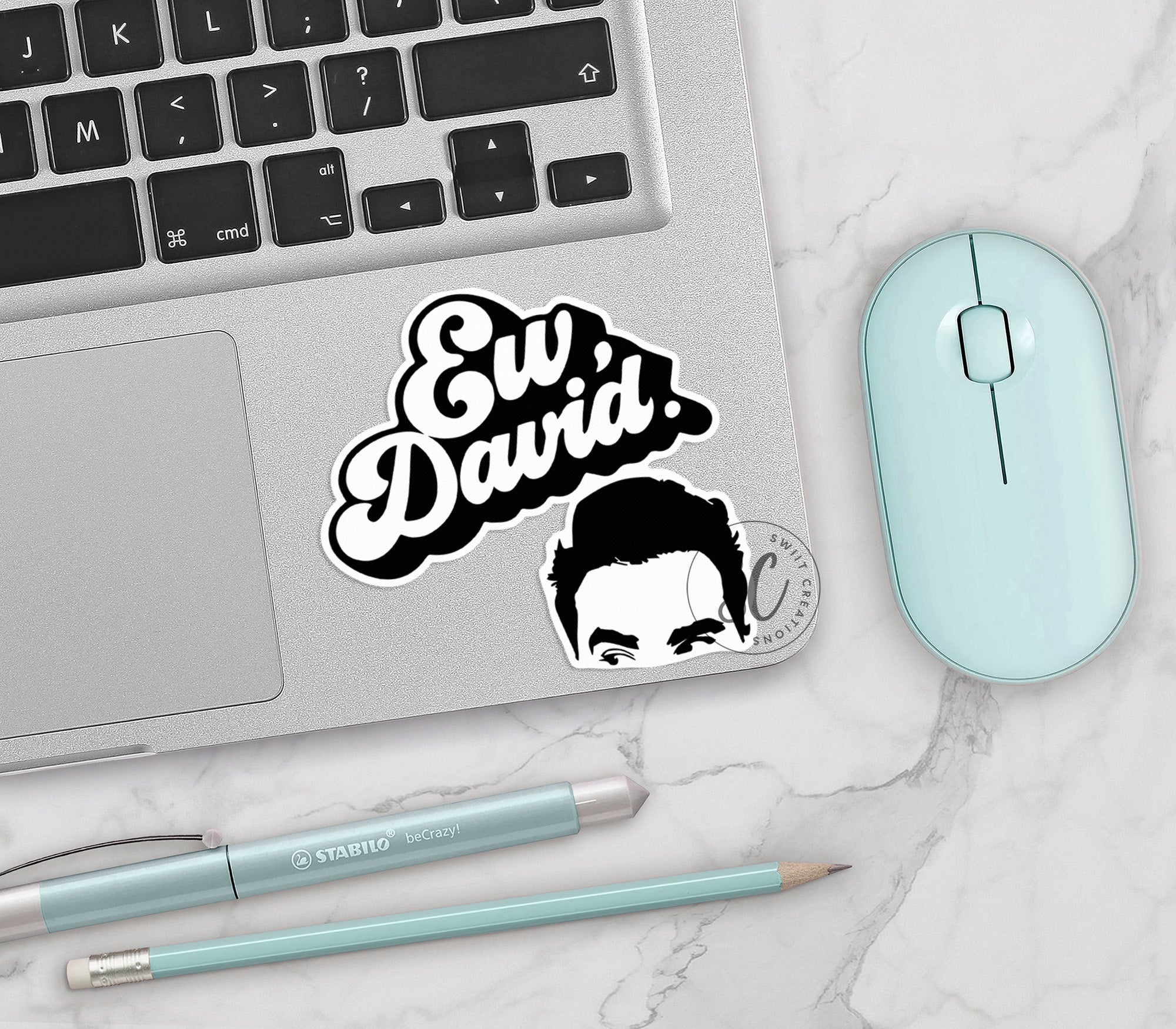 a laptop with a sticker of a man's face next to a mouse