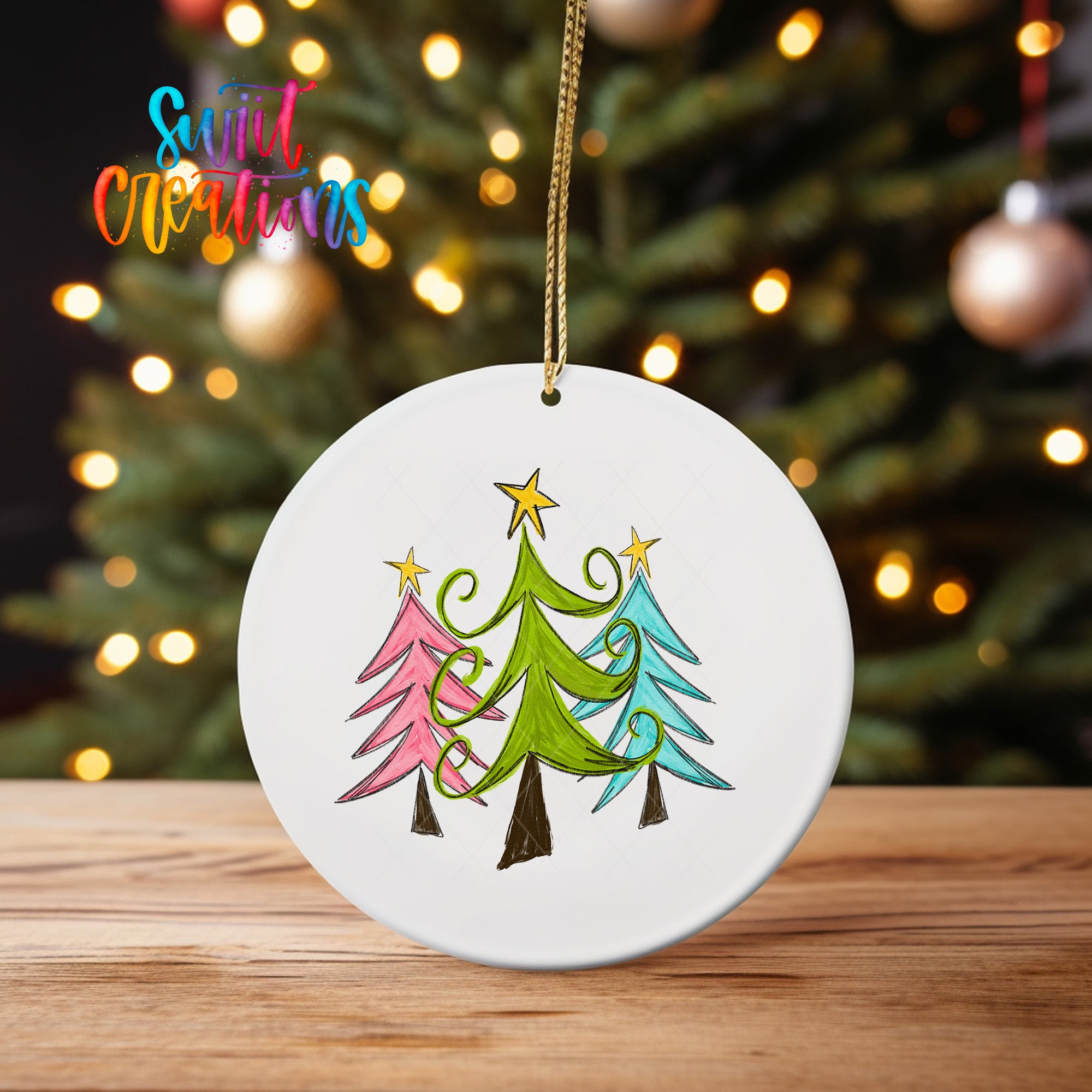 A white ceramic ornament with a colorful illustration of three stylized Christmas trees in various shades of green, pink, and blue, hanging from a string.