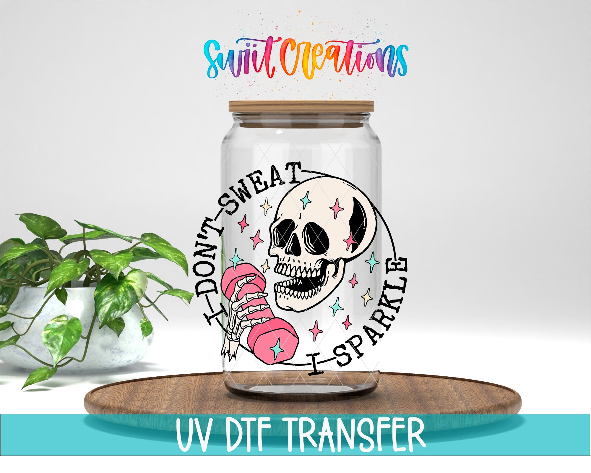 a glass jar with a skull design and the text "I DON'T SWEAT I SPARKLE" printed on it. The jar is placed on a wooden surface, and there is a potted plant in the background.
