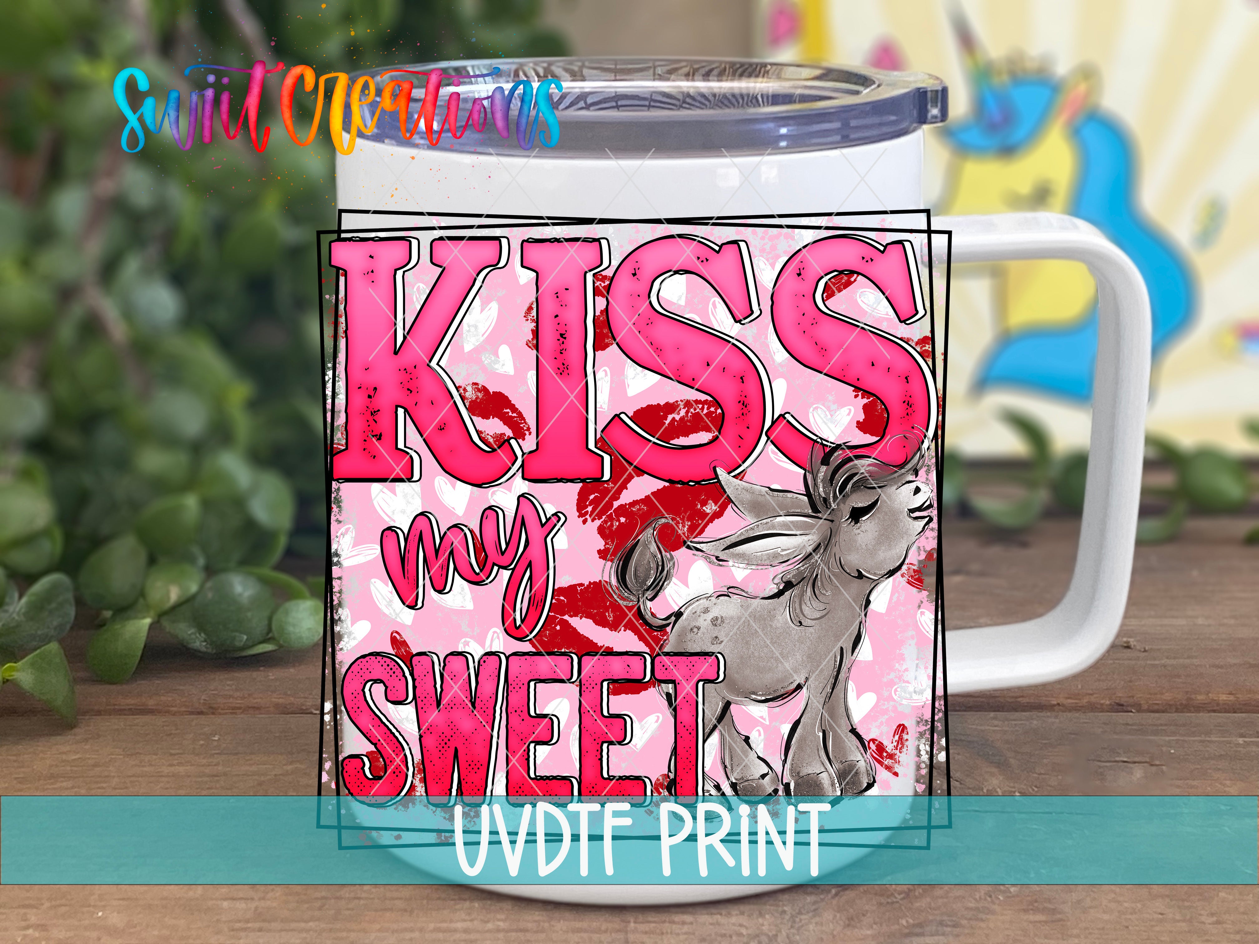 A white mug with a pink and black design featuring the text "KISS MY SWEET" and an illustration of a cartoon character.