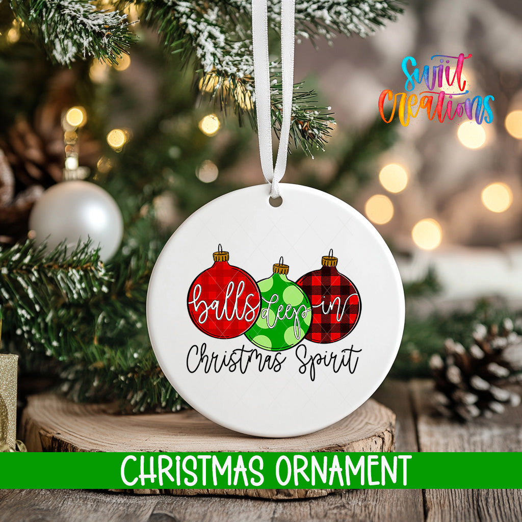 A white Christmas ornament with the text "balls keep in christmas spirit" and three Christmas ornaments in red, green, and black plaid colors, hanging on a tree branch.