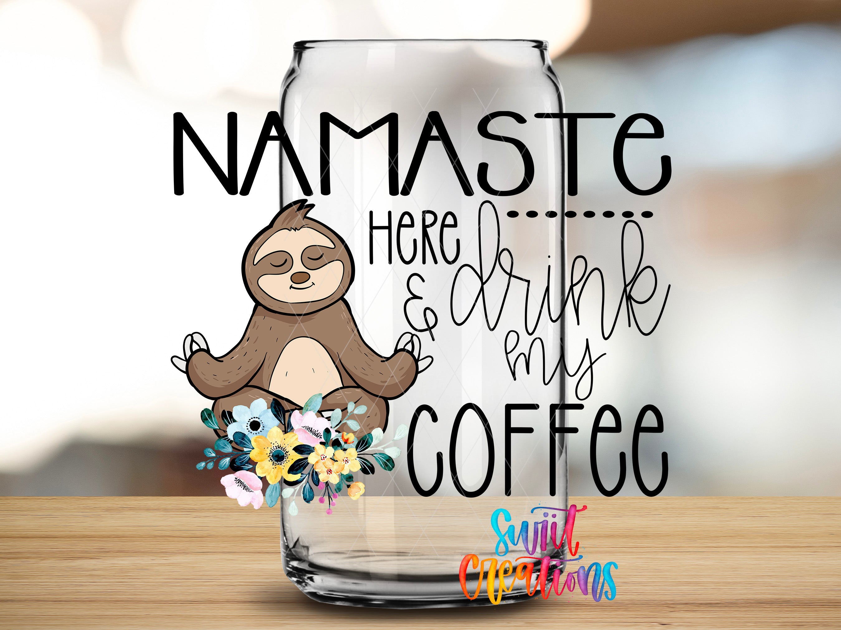 A glass mug with a sloth illustration and text that says "NAMASTE here... drink my COFFEE"