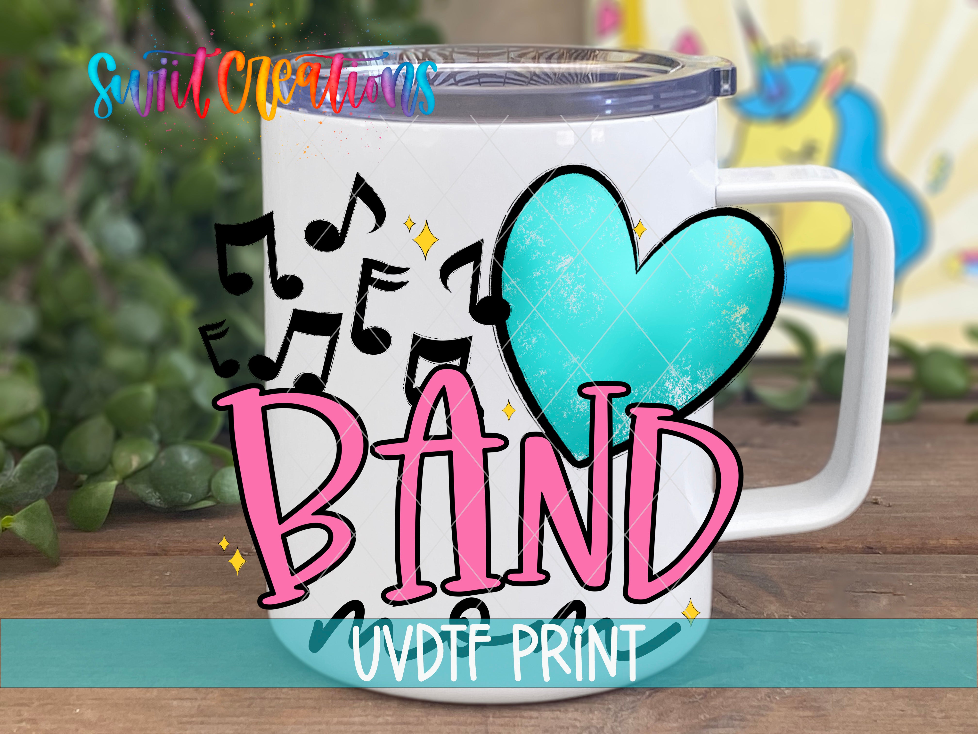 A white mug with the word "BAND" written on it, along with musical notes and a heart shape. The mug is placed on a wooden surface, and there is a colorful background behind it.