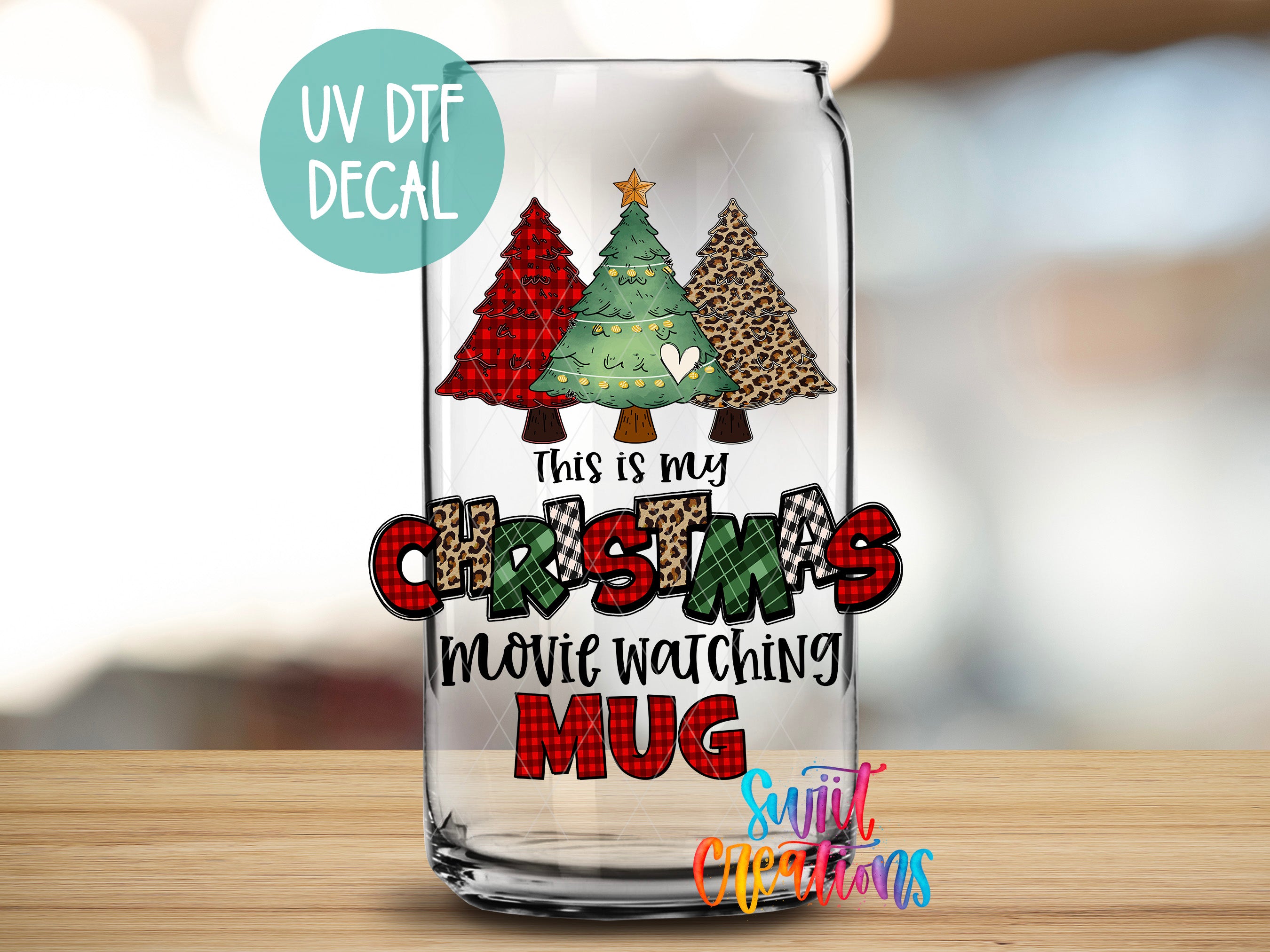 A glass mug with a Christmas tree decal on it, featuring a message that says "This is my Christmas movie watching mug".