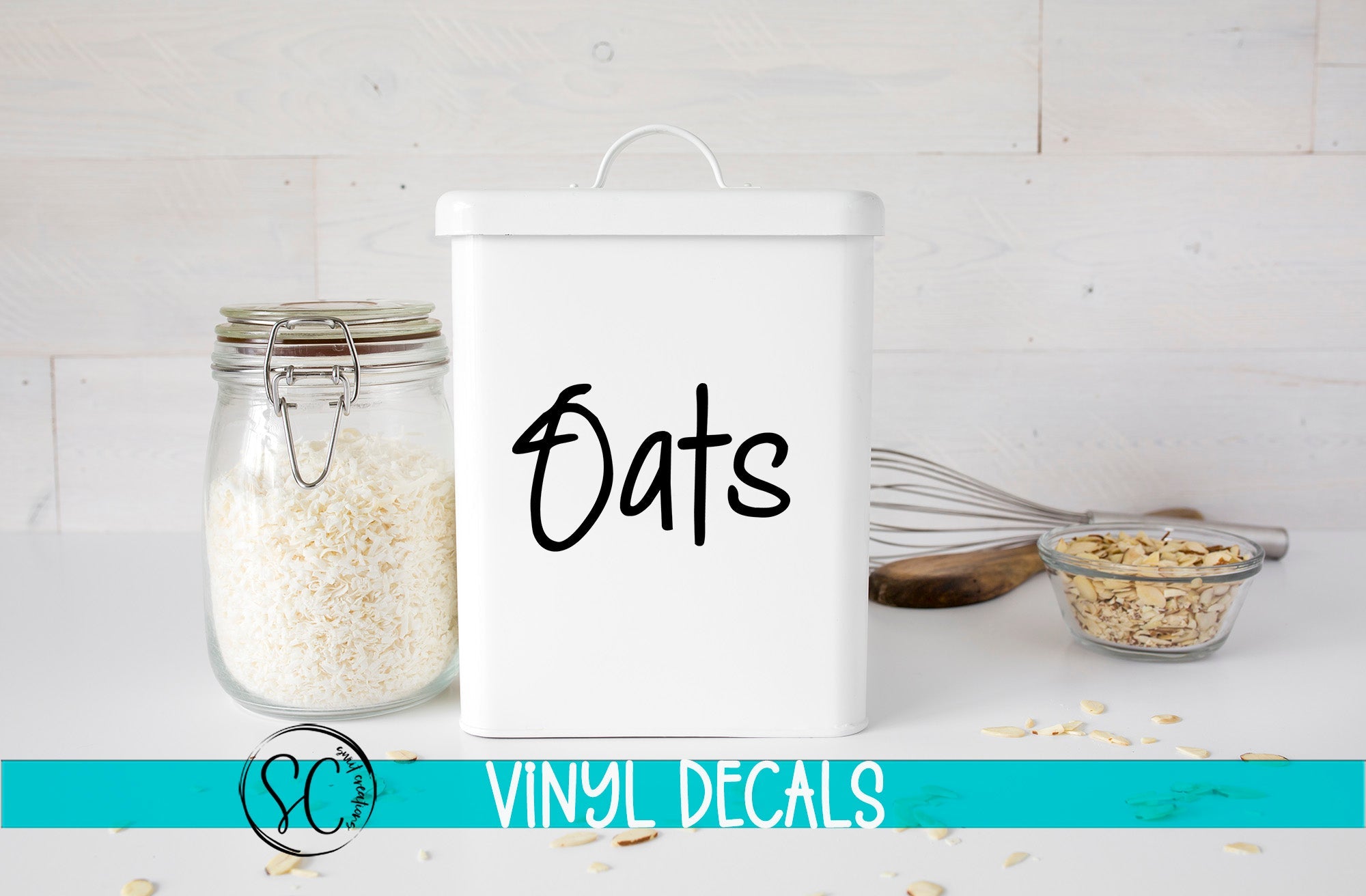 a white canister labeled "Oats" next to a glass jar filled with rice, with a whisk and a bowl of nuts on a white countertop.