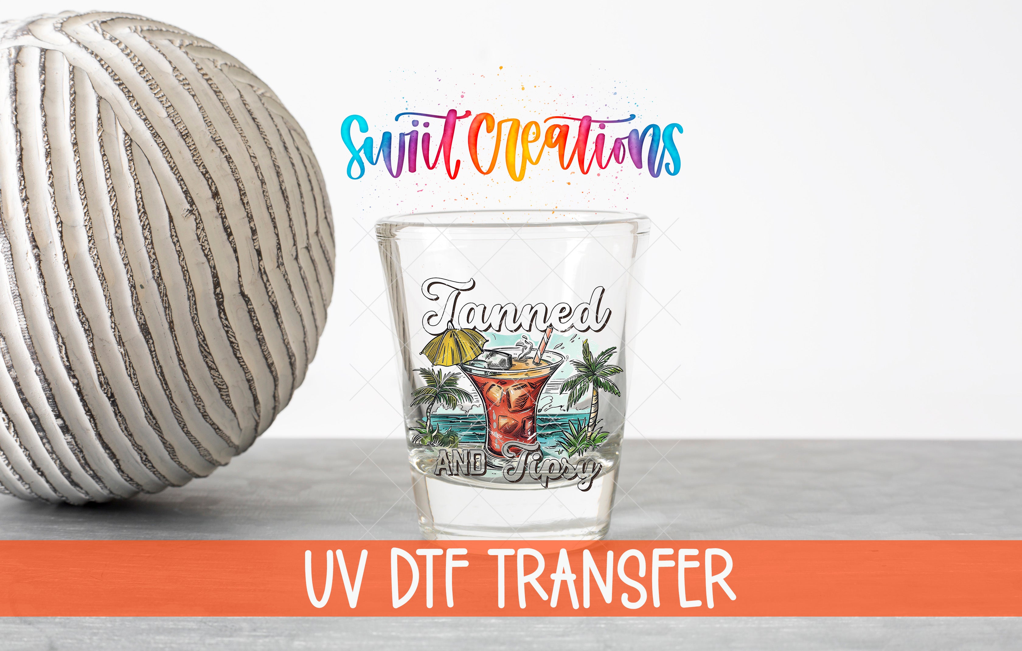 a shot glass with a tropical drink design and the text "Tanned and happy" printed on it, along with a colorful watermark that says "Swit Creations" and "UV Dtf Transfer".