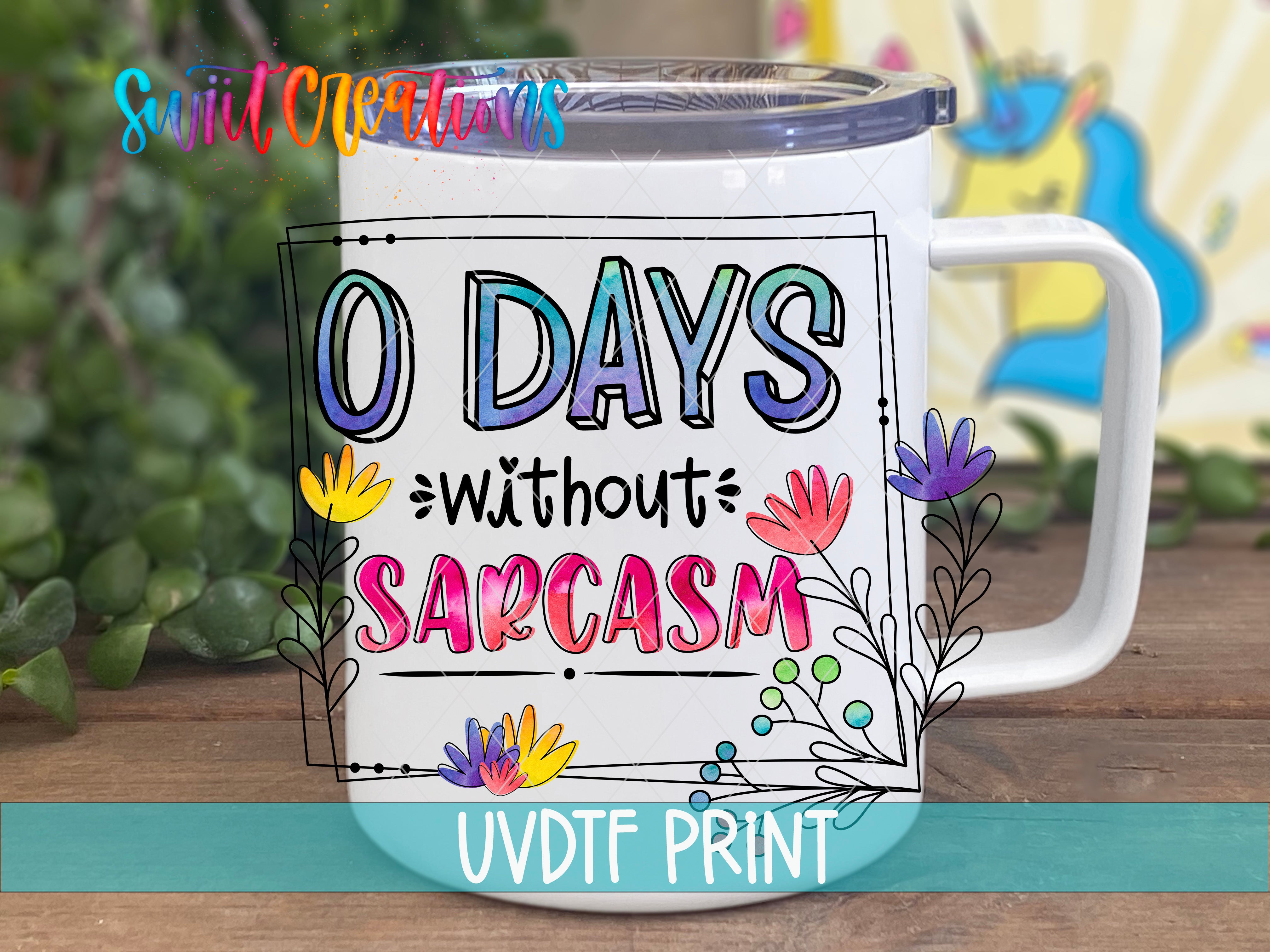 A white mug with colorful text and floral designs, placed on a wooden surface.