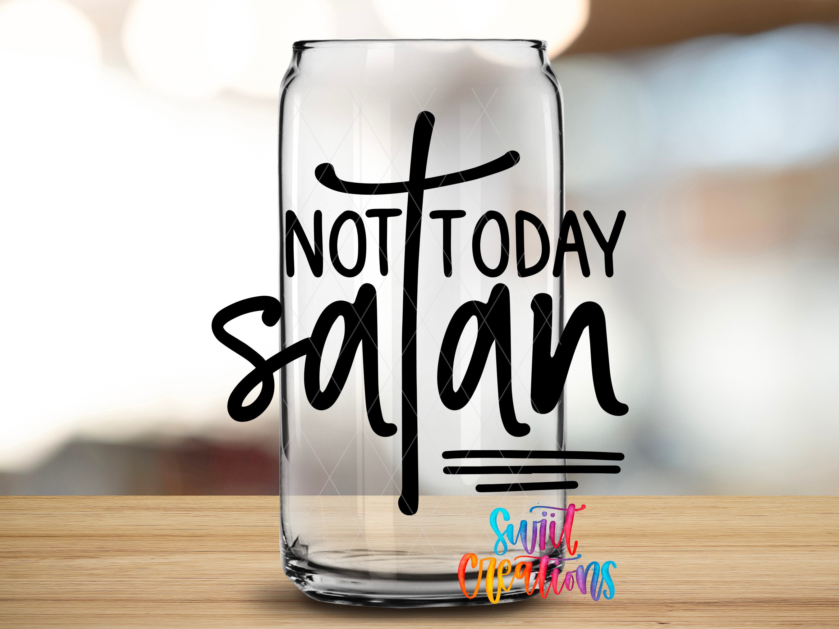 A clear glass can with the text "NOT TODAY SATAN" printed on it, placed on a wooden surface.