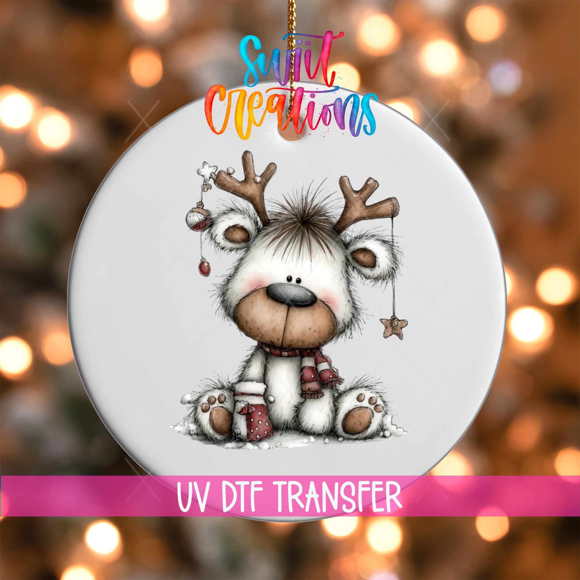 A white ornament with a cartoon reindeer and Christmas decorations, including a star and a ball, is displayed against a blurred background with colorful lights.