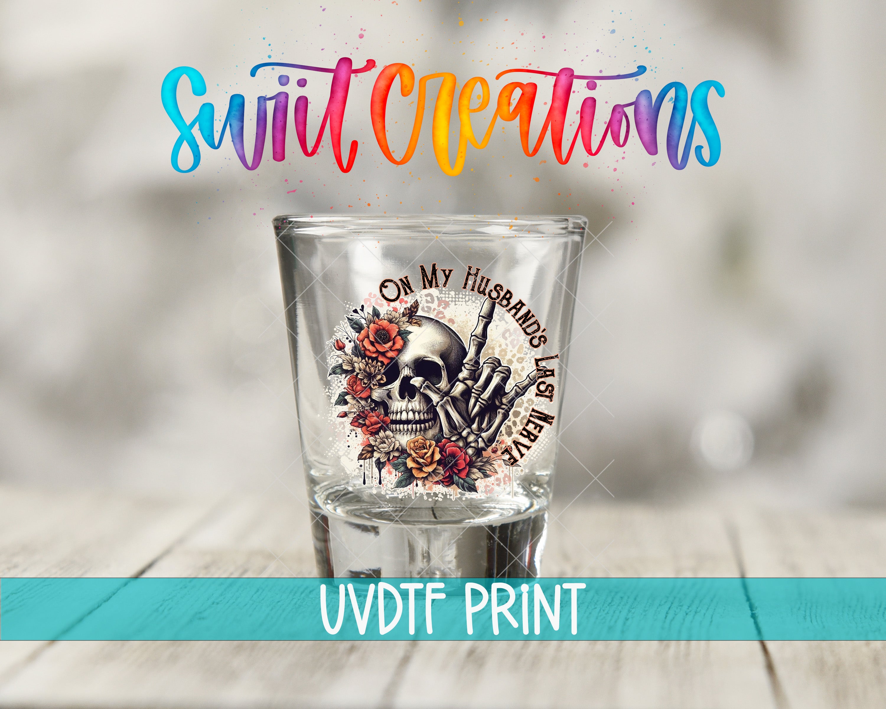 a shot glass with a skull design and floral elements, placed on a wooden surface.