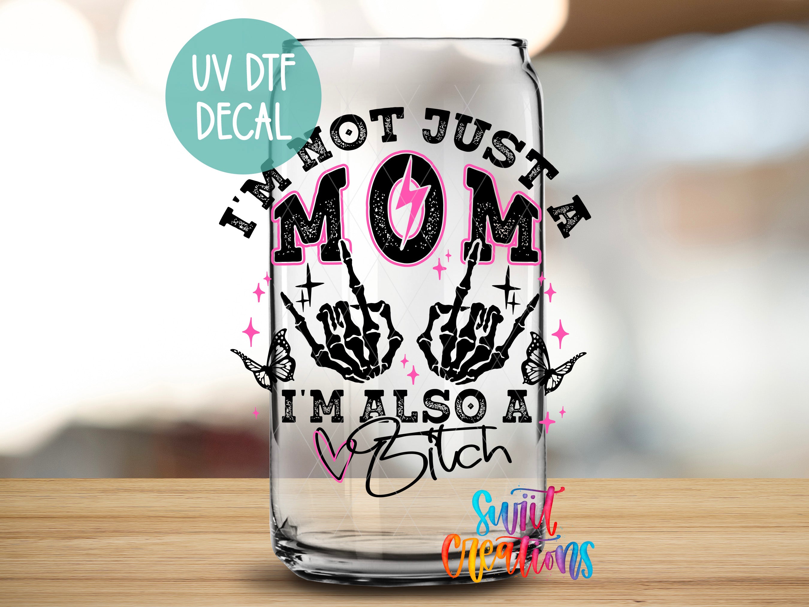 A glass with a sticker on it, featuring a humorous and unconventional message about being a "not just mom, but also a bitch".