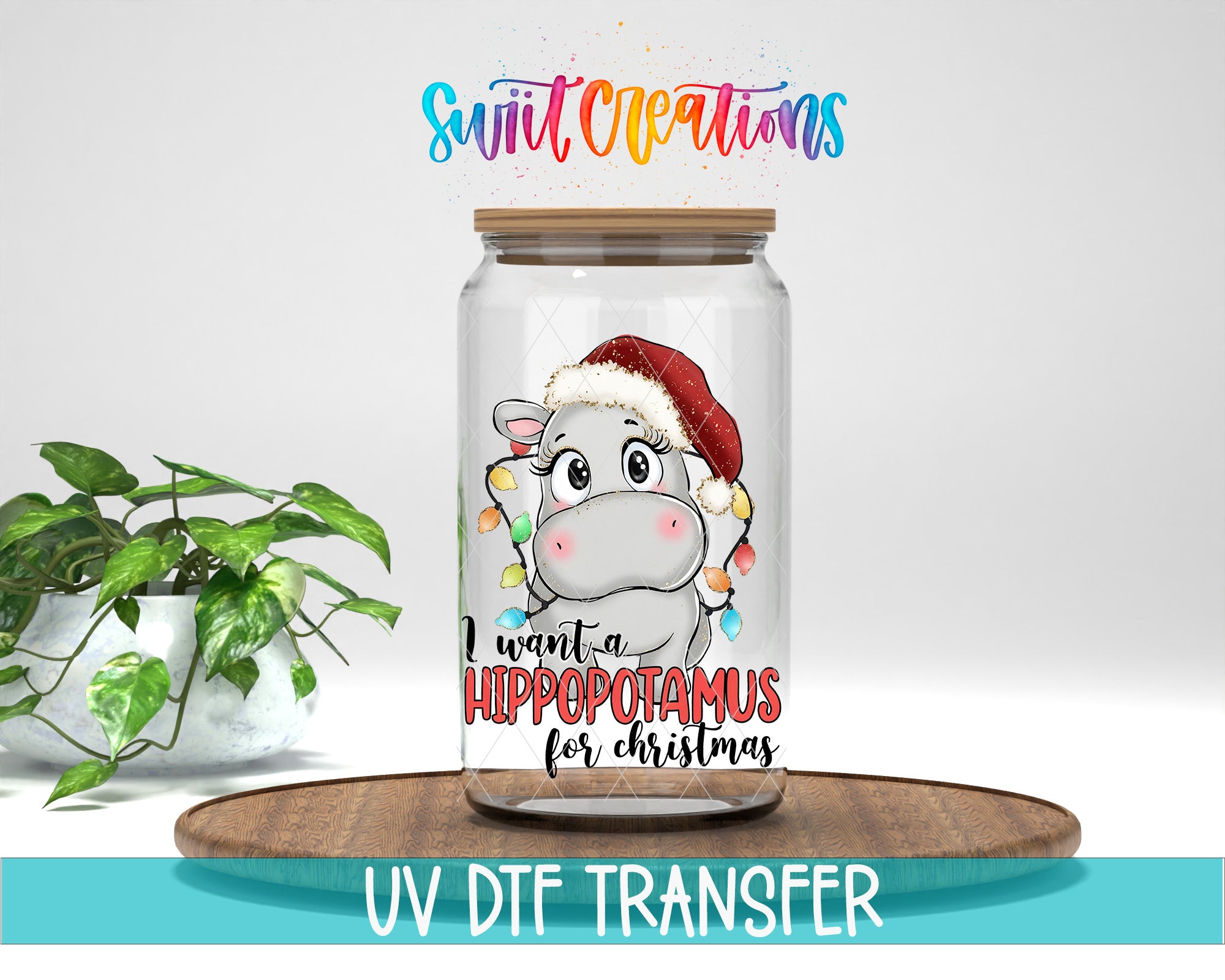 A glass jar with a cartoon image of a hippopotamus wearing a Santa hat, along with text that says "I want a Hippopotamus for Christmas". The jar is placed on a wooden surface, and there is a potted plant in the background.
