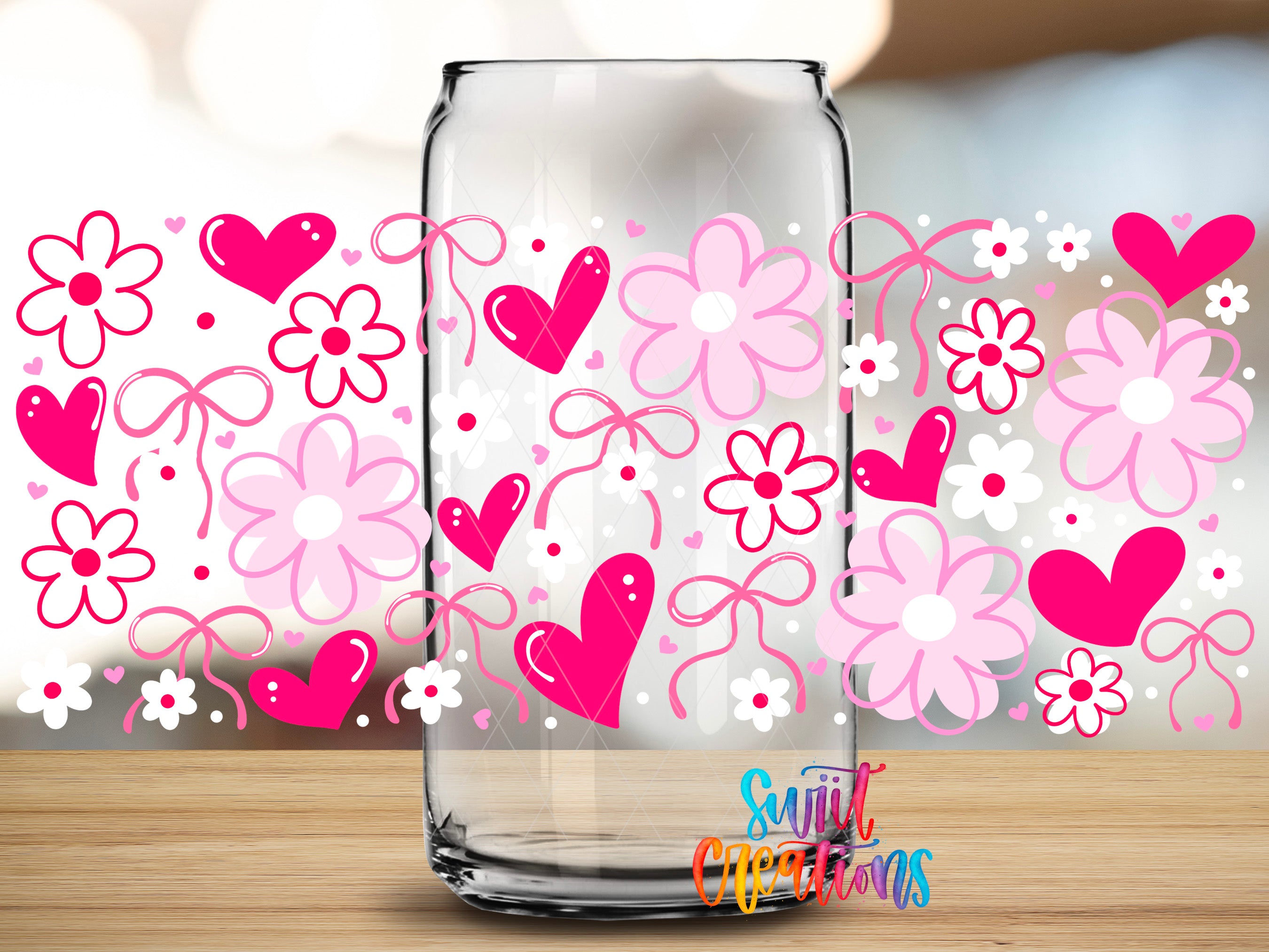 A clear glass jar with a floral pattern of pink flowers and hearts on it, placed on a wooden surface.