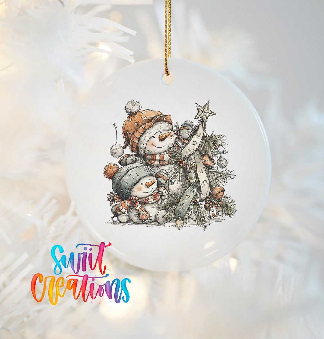 A white ornament with a snowman and star on a Christmas tree, hanging on a string.