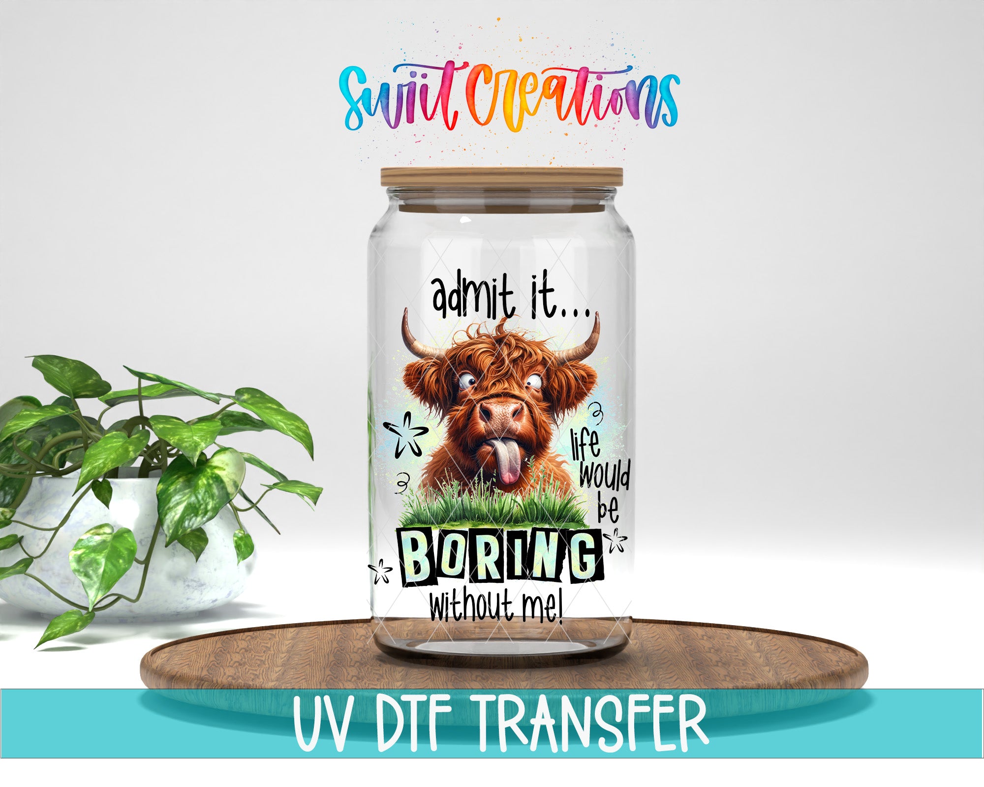 A glass jar with a picture of a cow and the text "admit it... life would be boring without me!" inside, placed on a wooden surface next to a potted plant.