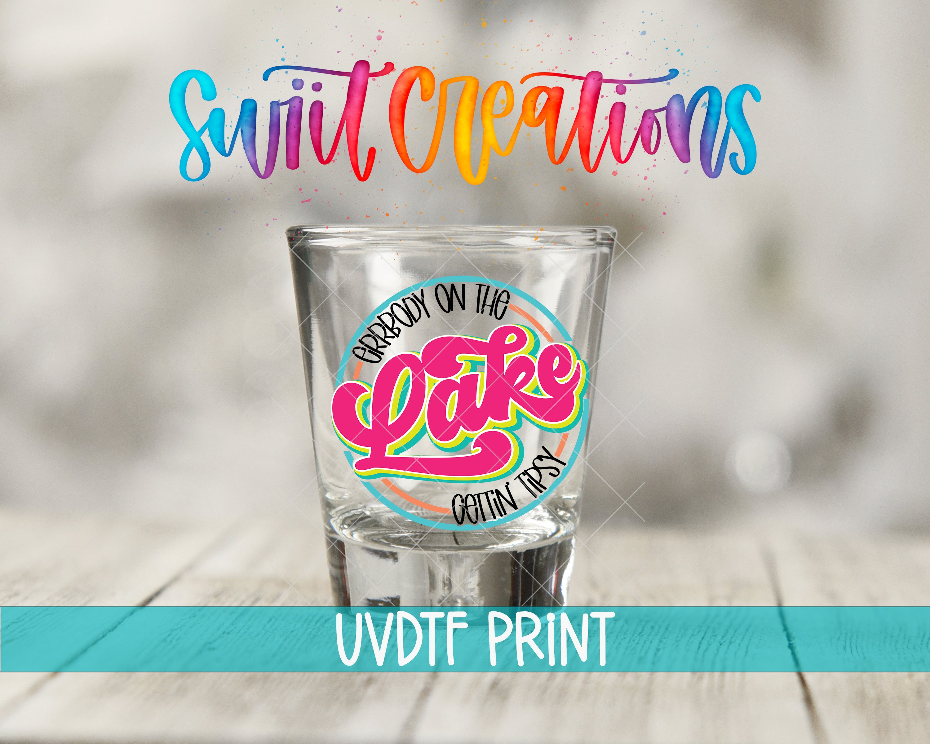 a shot glass with a colorful, hand-drawn design on it, placed on a wooden surface.