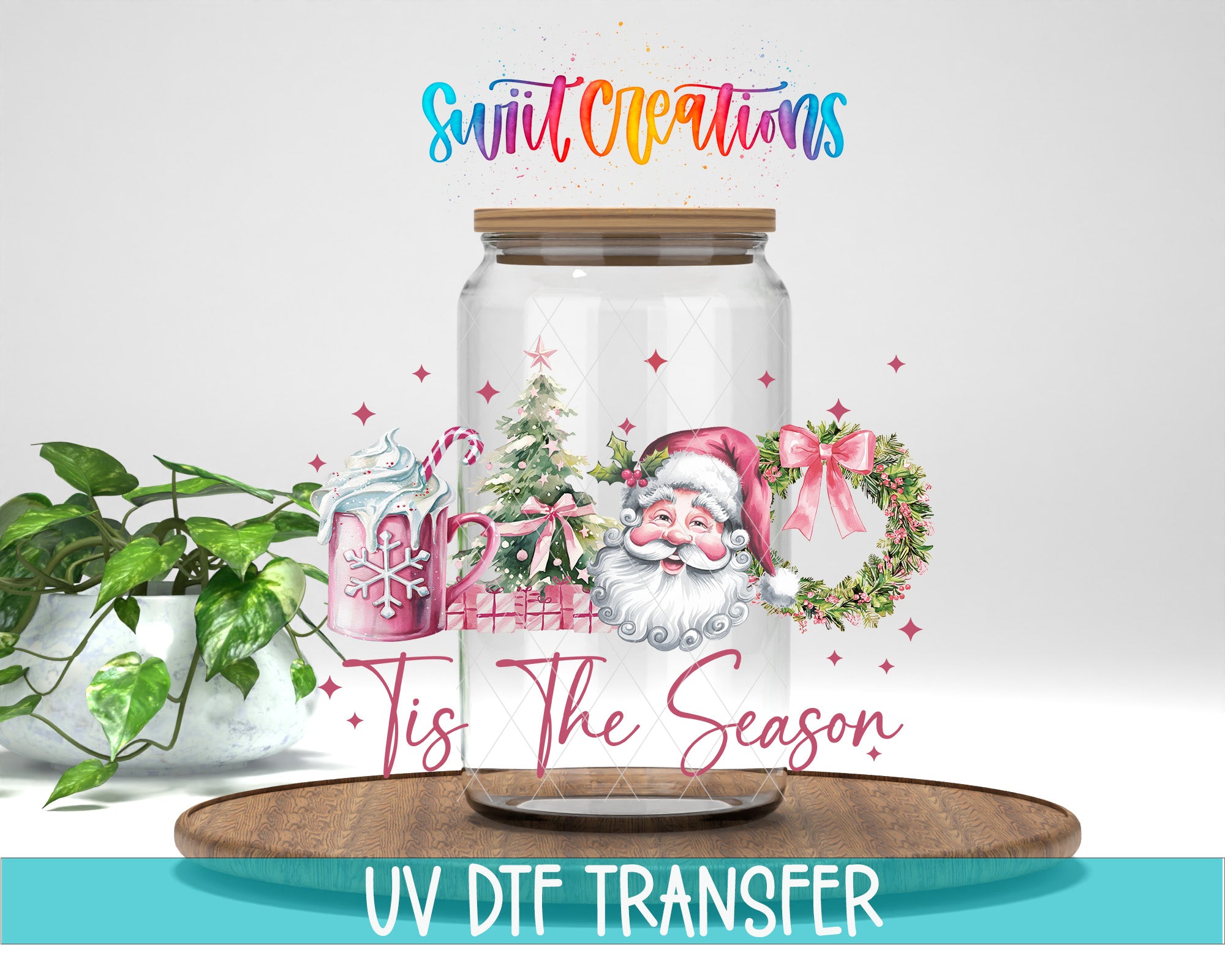 A glass jar with a Santa Claus illustration and Christmas decorations, along with the text "Tis the Season" and "Swift Creations" written on it. The jar is placed on a wooden tray, and there is a potted plant in the background.