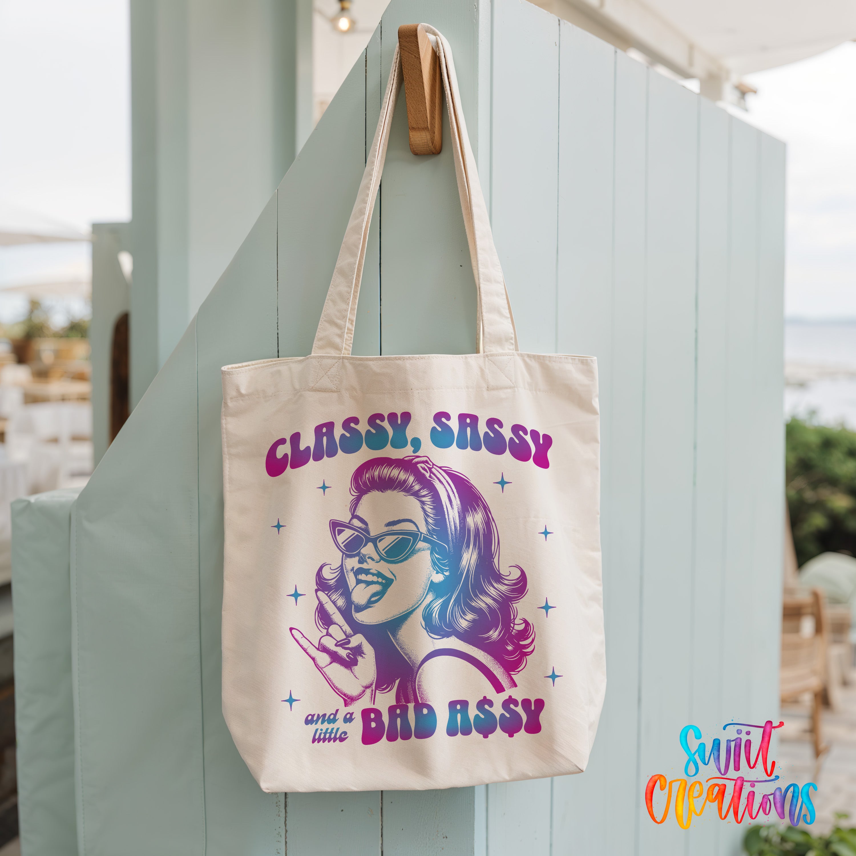 A white tote bag with a colorful graphic design featuring a woman's face and the text "CLASSY SASSY and a little BAD ASSY" printed on it.
