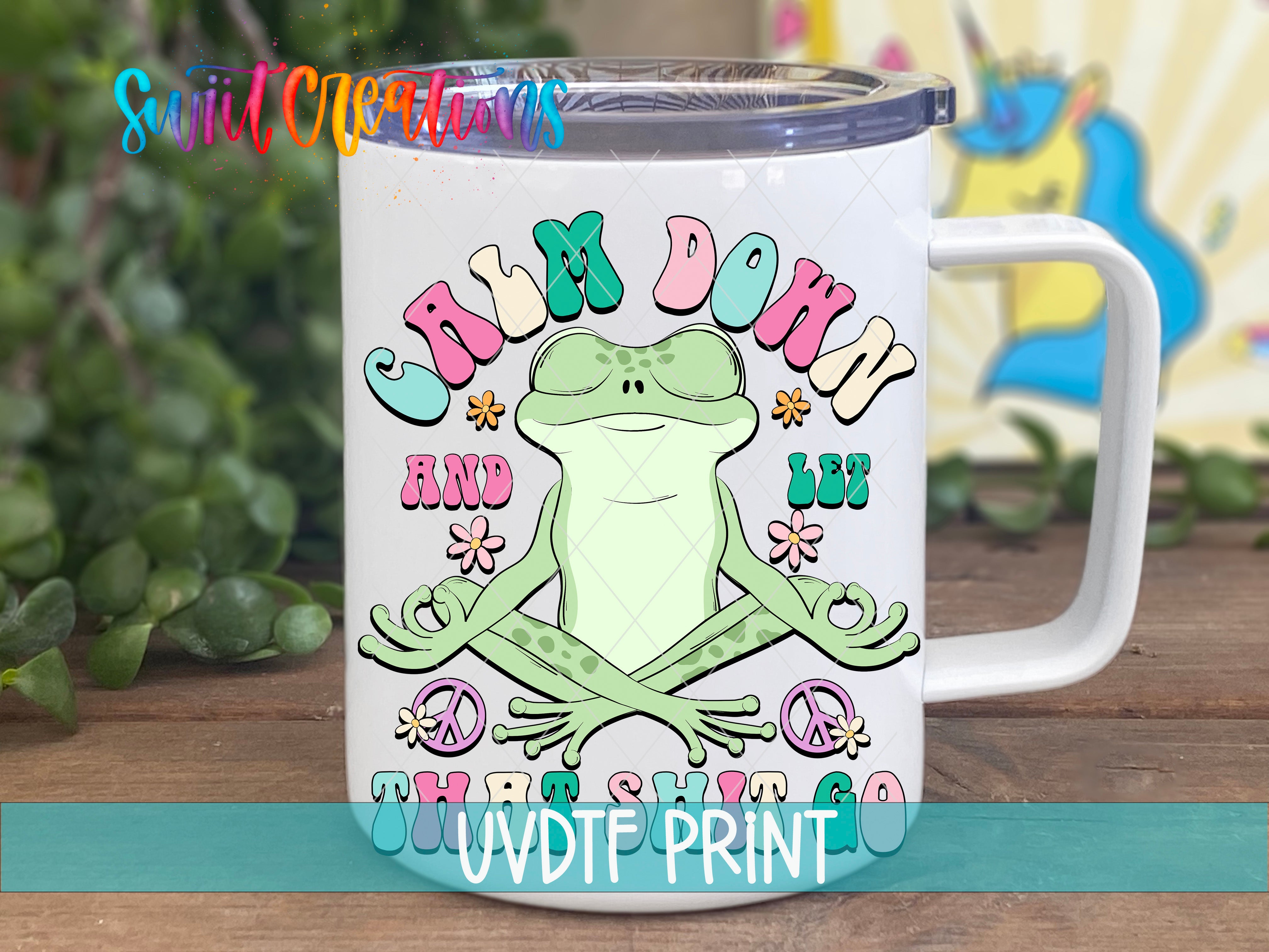 A white mug with a colorful design featuring a frog and the text "Calm Down" and "Let Go".