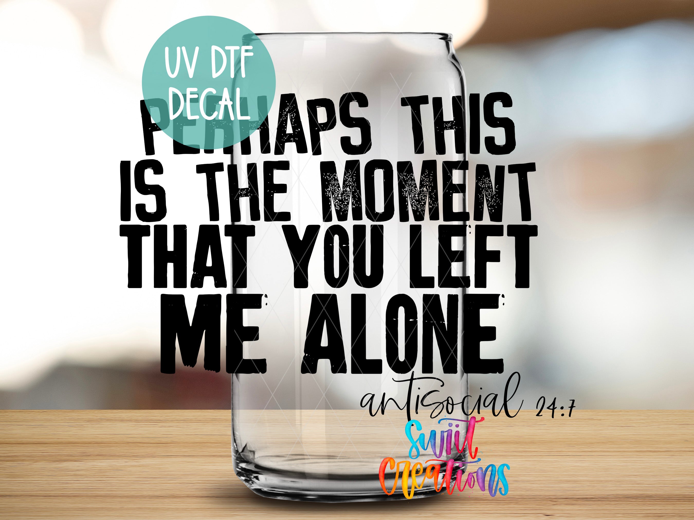 a glass with text on it, placed on a wooden surface.