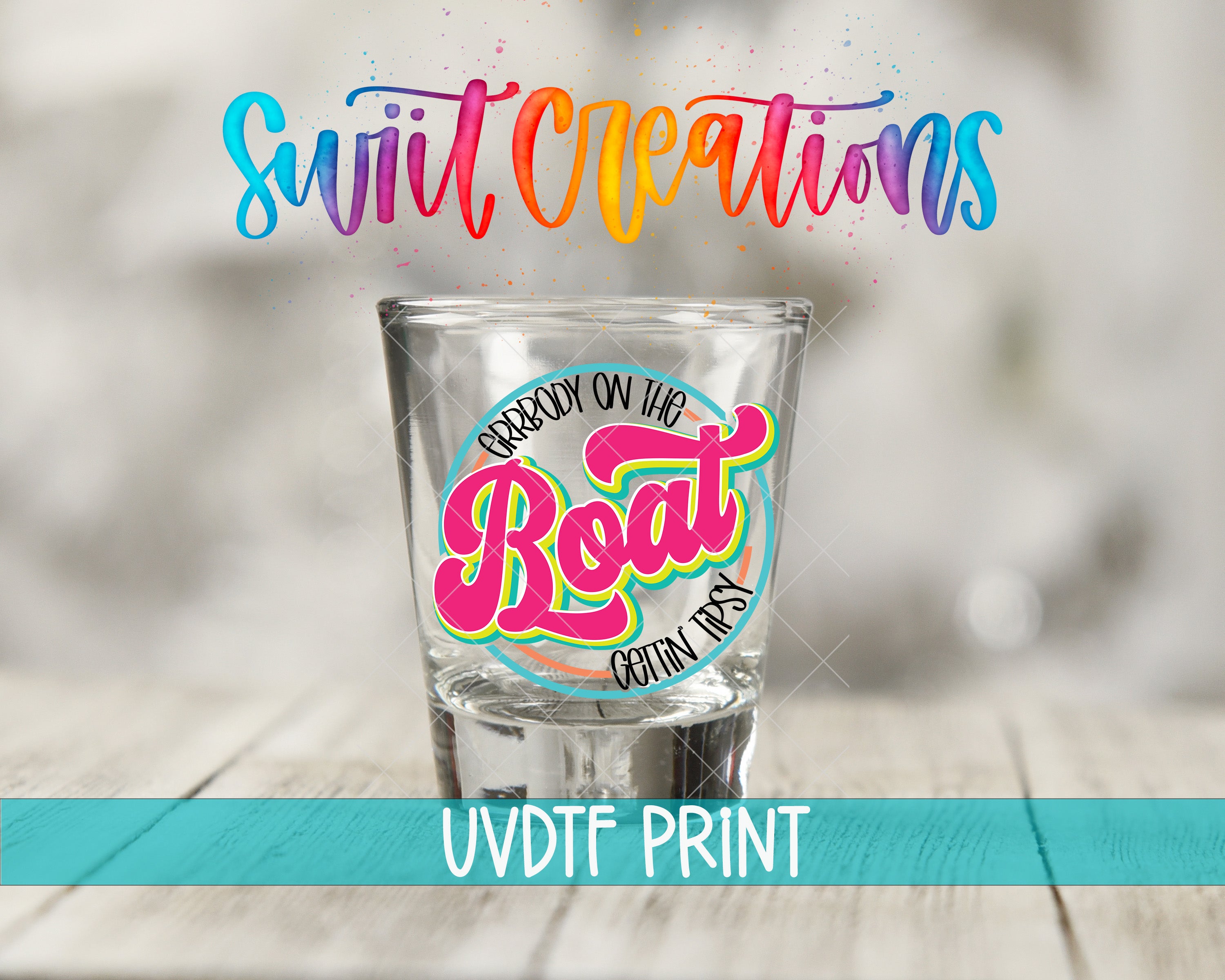 a shot glass with a colorful, hand-lettered design on it, placed on a wooden surface.
