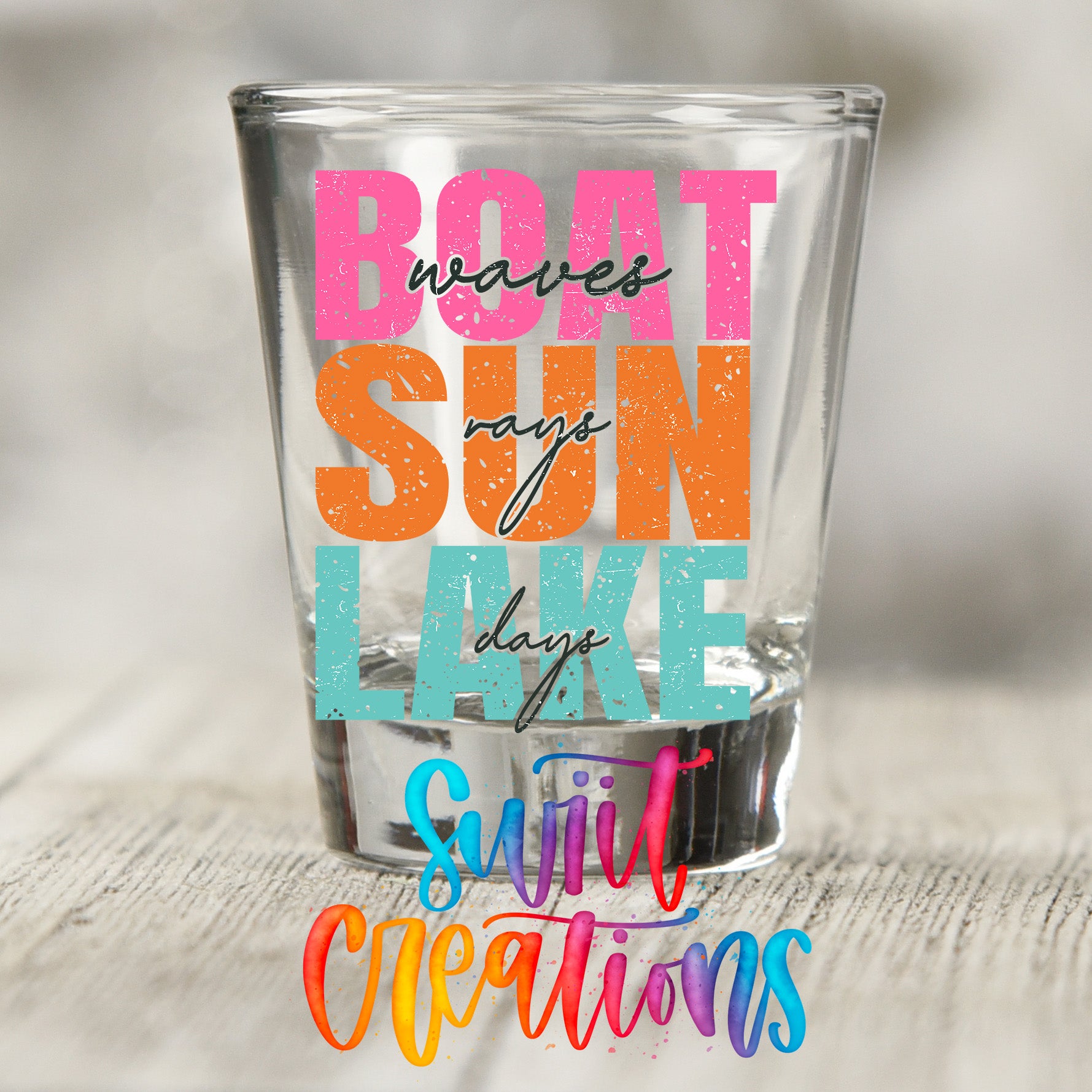 a colorful glass with text on it, placed on a wooden surface.