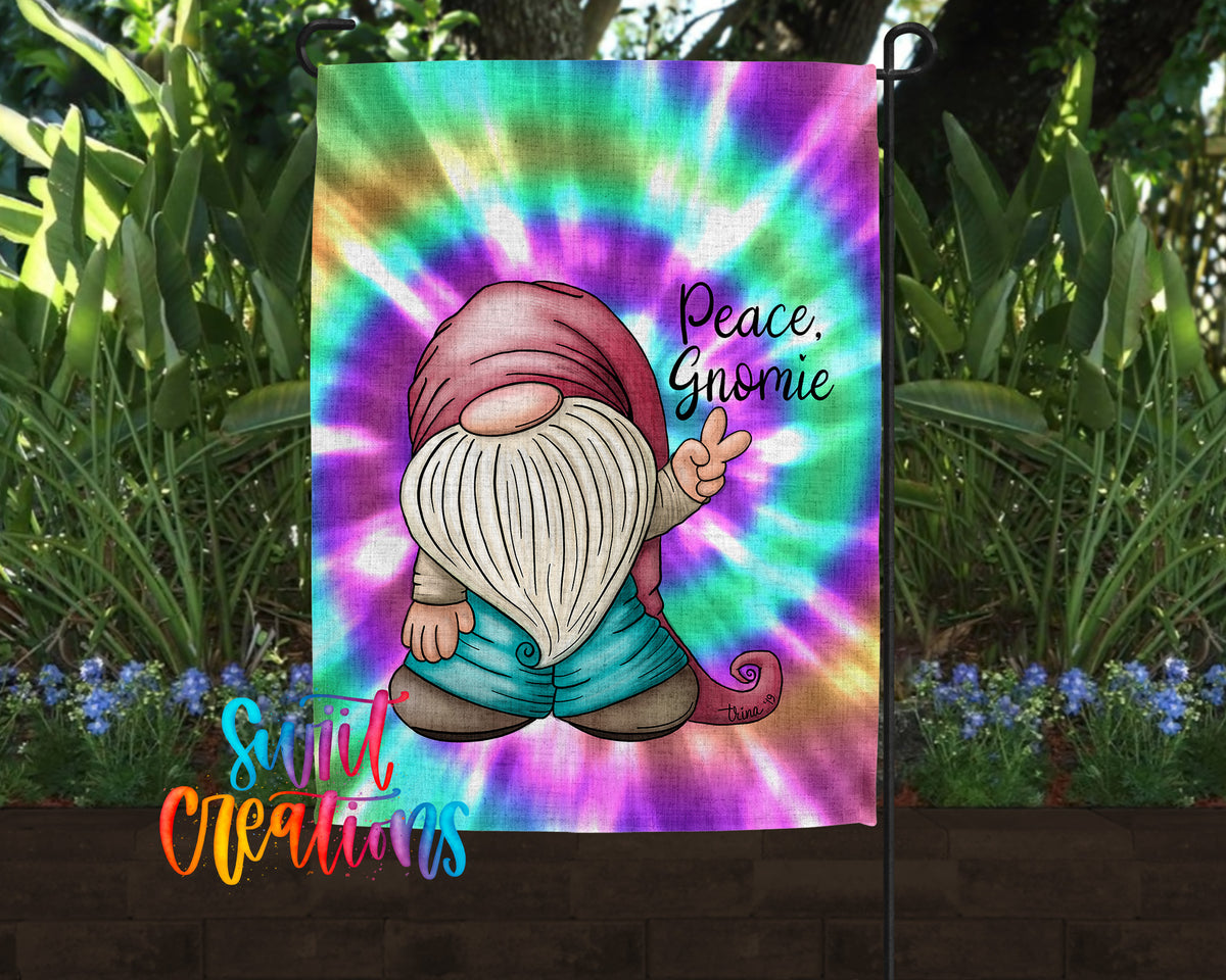 A colorful garden flag featuring a gnome character with a peace sign, surrounded by a tie-dye background and greenery.