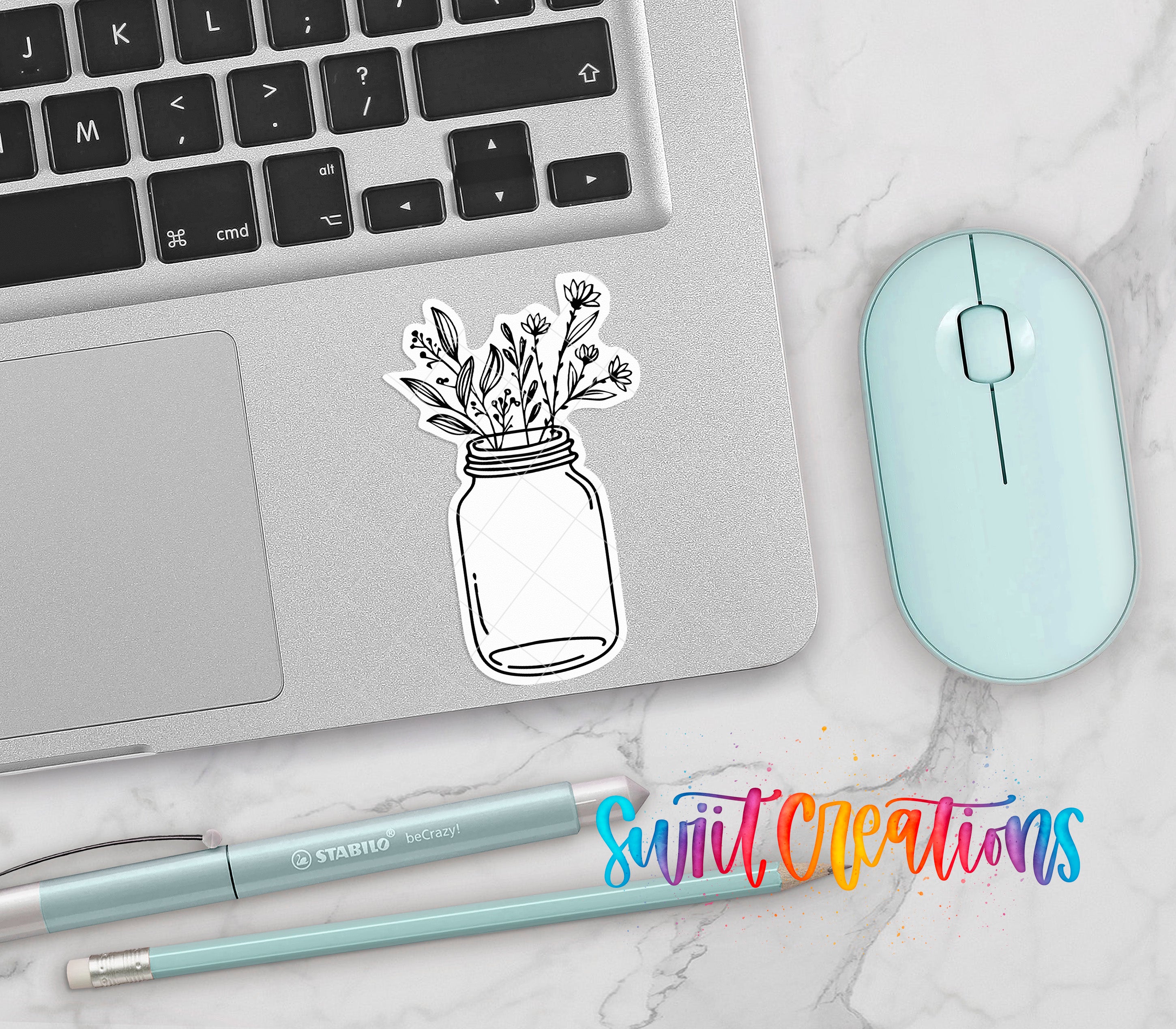 a laptop with a sticker of a jar containing flowers, a mouse, a pen, and a pencil on a marble surface.