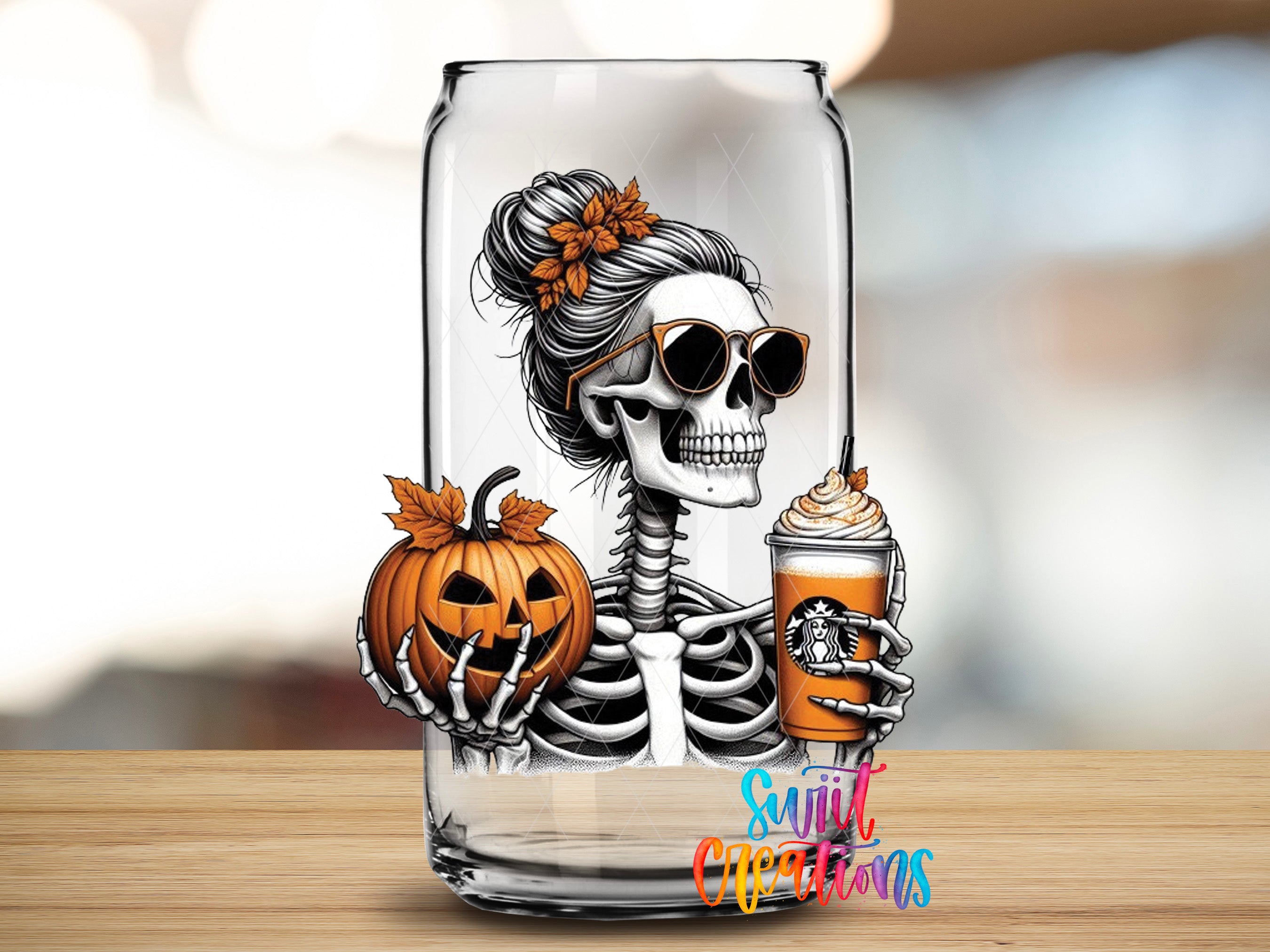 A glass can with a skeleton wearing sunglasses and holding a pumpkin and a Starbucks drink, set against a blurred background.