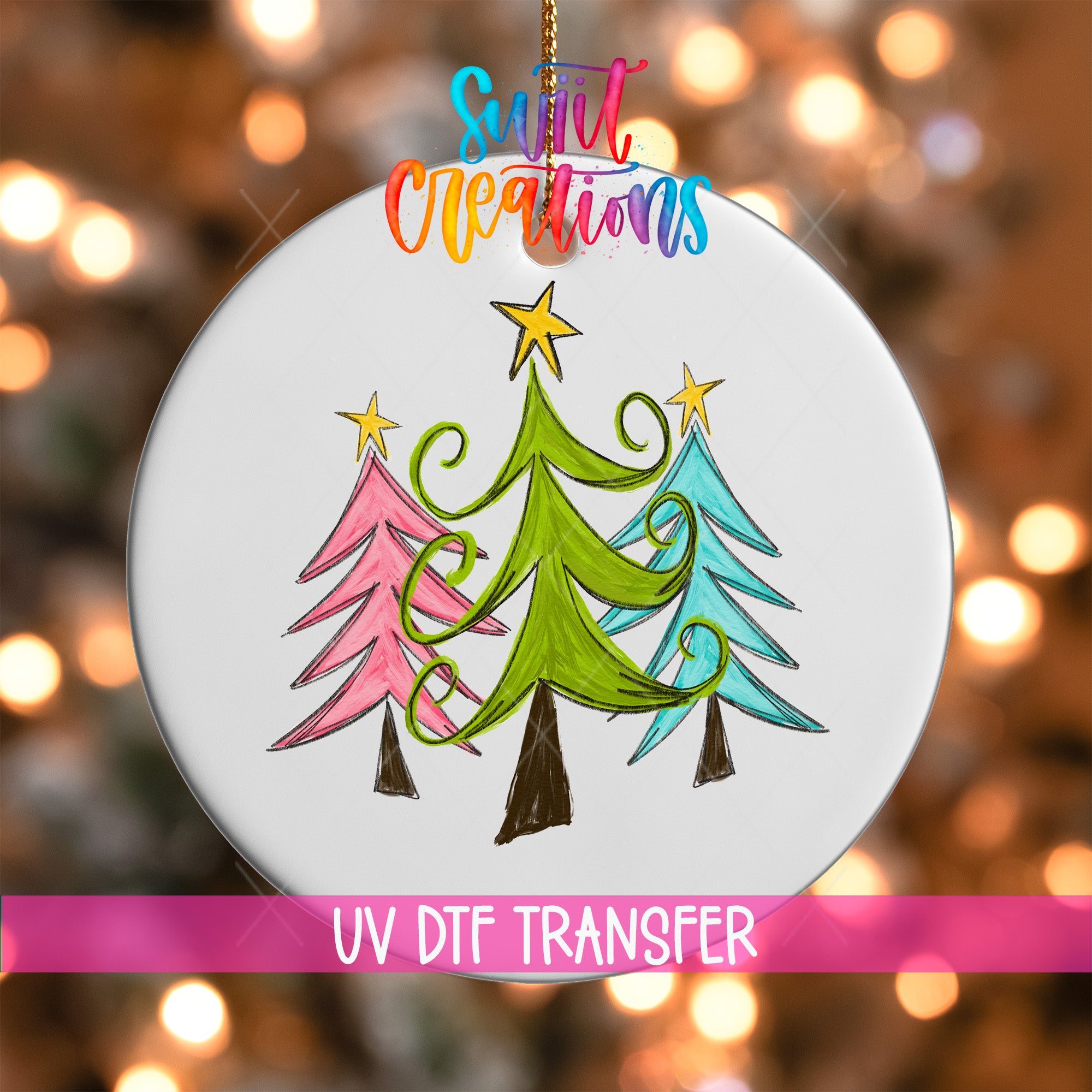 A white ornament with a colorful illustration of three stylized Christmas trees, along with a star and a ribbon, hanging against a blurred background with colorful lights.