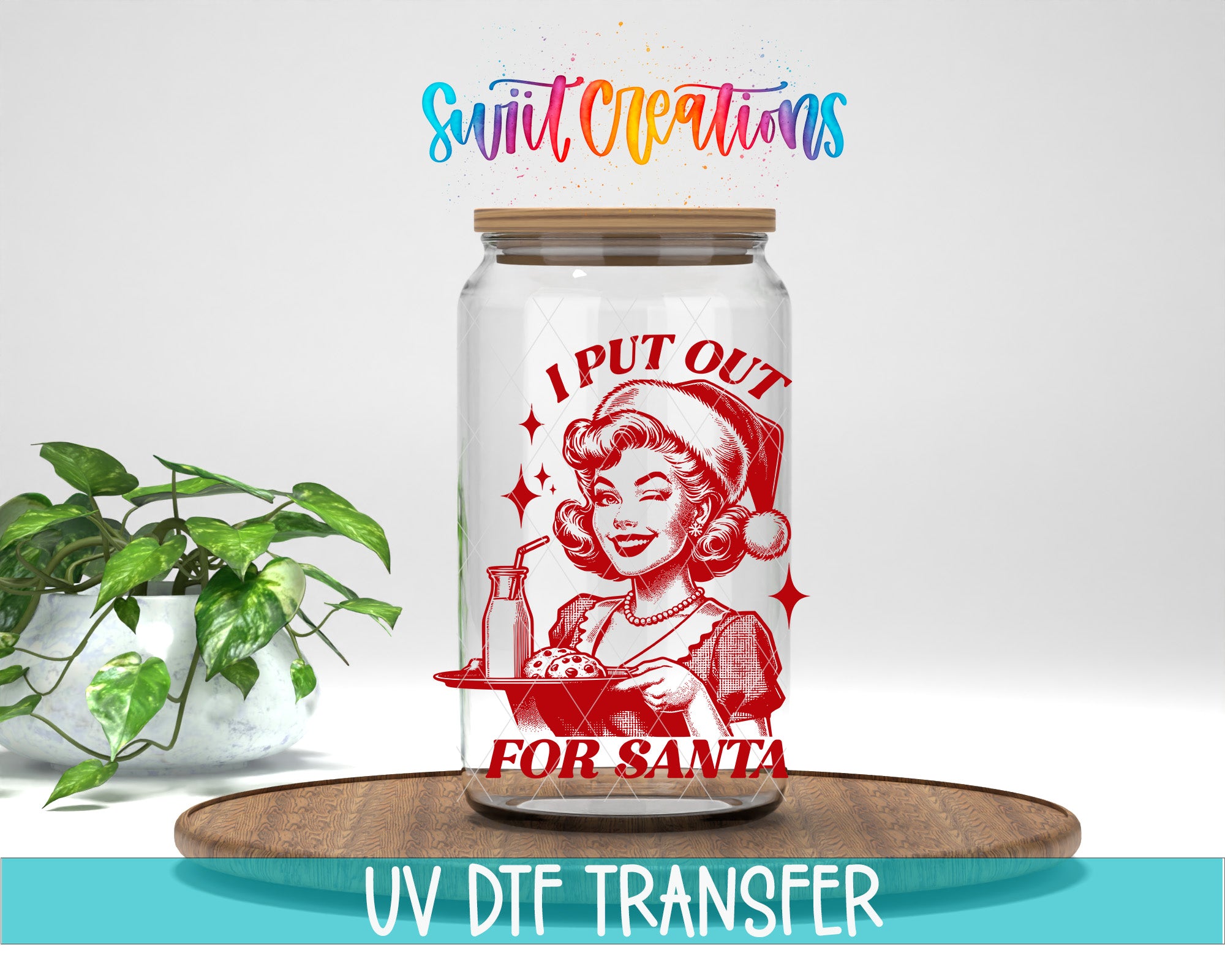A glass jar with a red and white illustration of a woman in a Santa hat, along with the text "I PUT OUT FOR SANTA" and "Swift Creations" written above it. The jar is placed on a wooden surface, and there is a potted plant in the background.