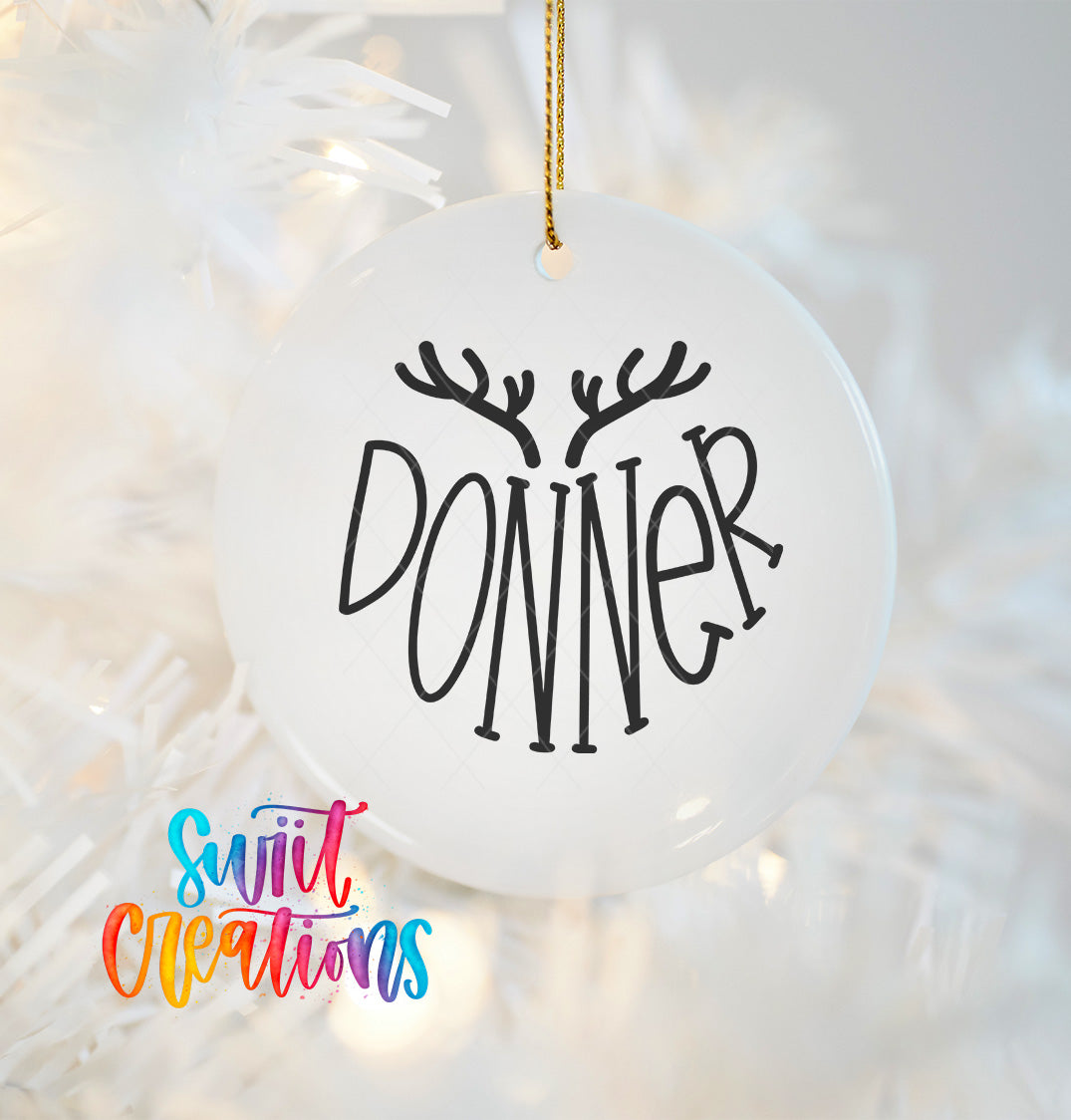 A white ornament with the word "DONNER" written on it, hanging on a Christmas tree.