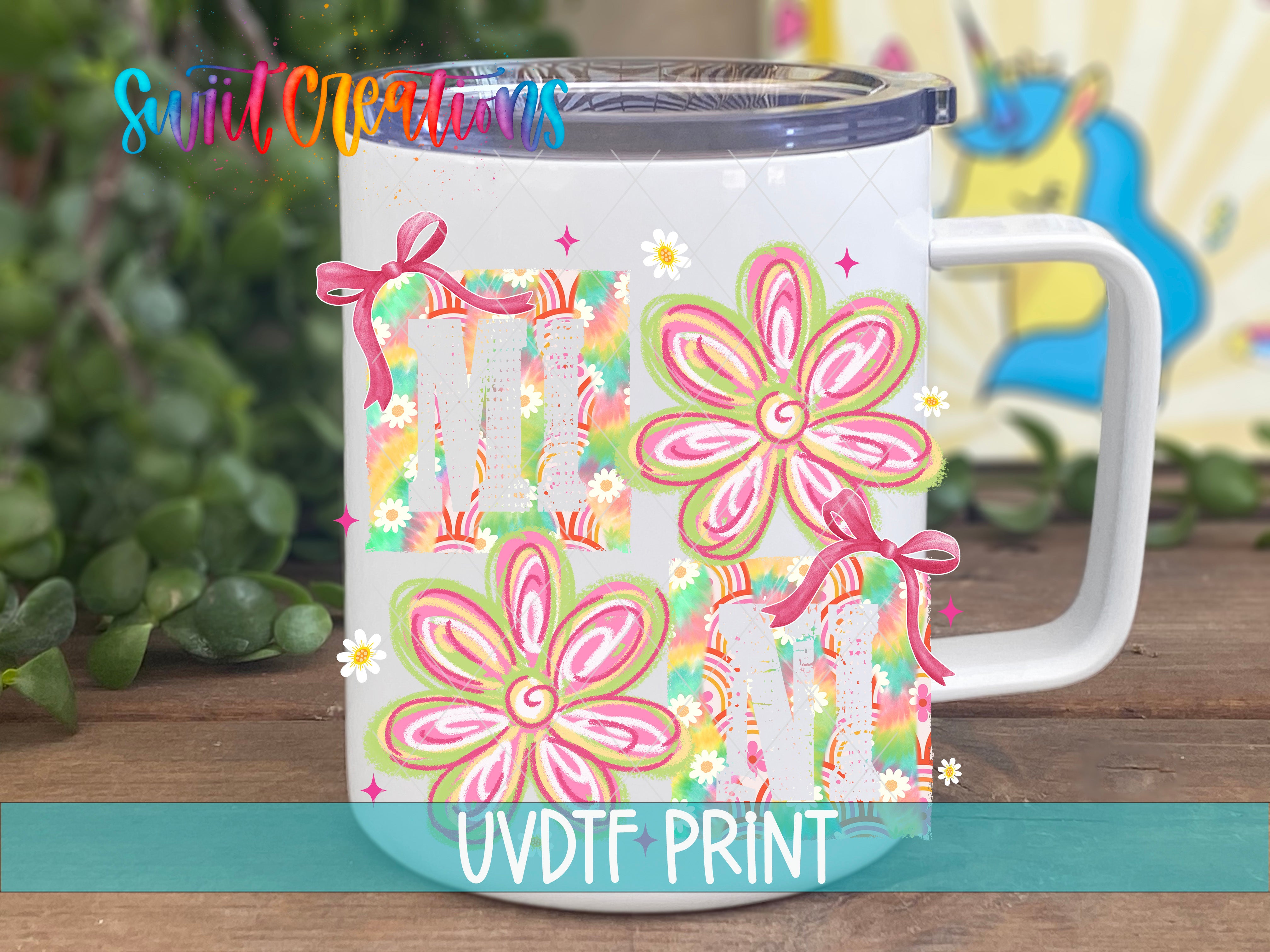 A white ceramic mug with colorful floral designs and the text "MUM" printed on it, placed on a wooden surface with a blurred background.