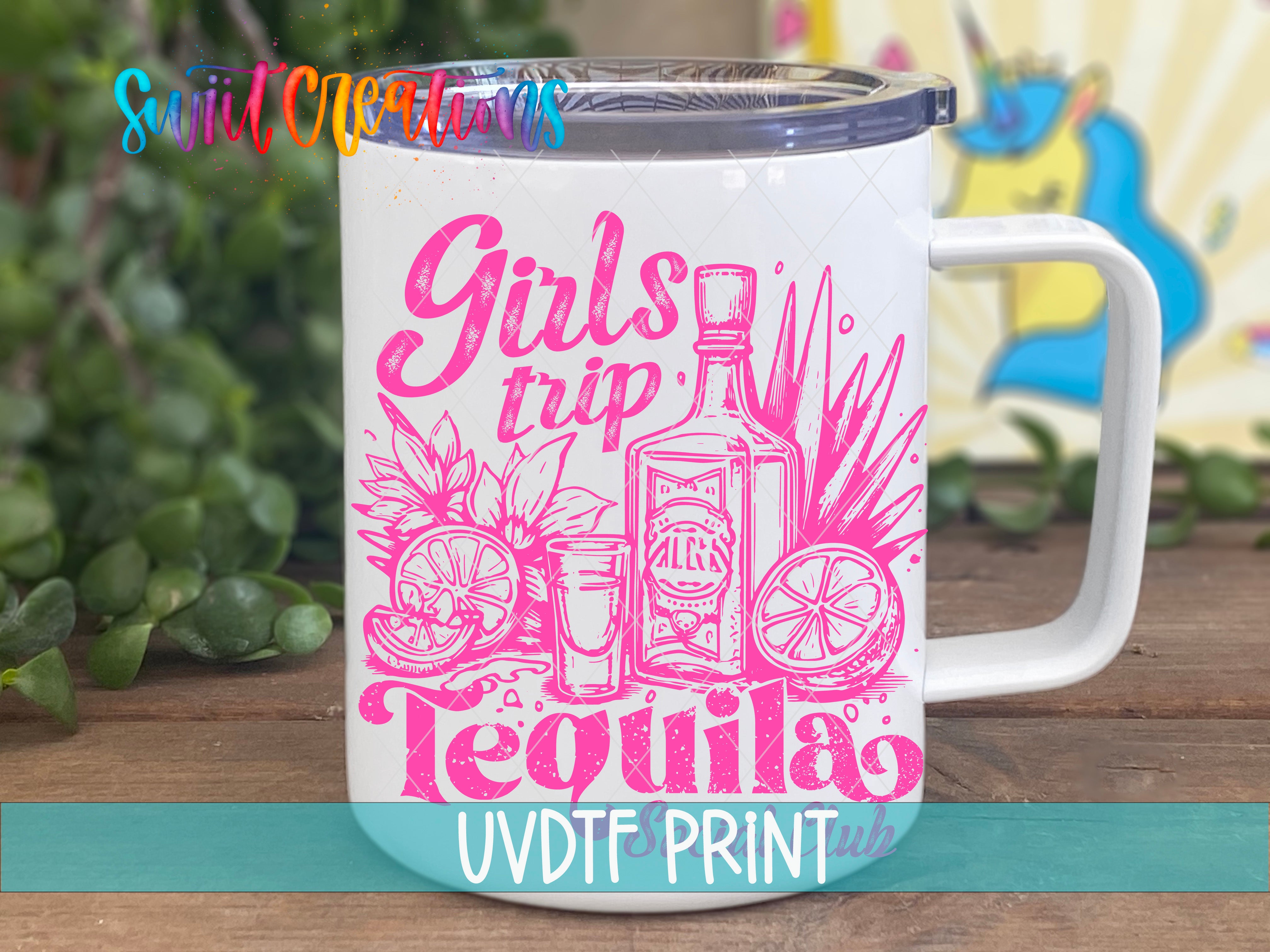 A white mug with a printed design featuring a bottle of tequila, a cocktail glass, and various tropical fruits, along with the text "Girls trip Tequila" in pink and yellow.