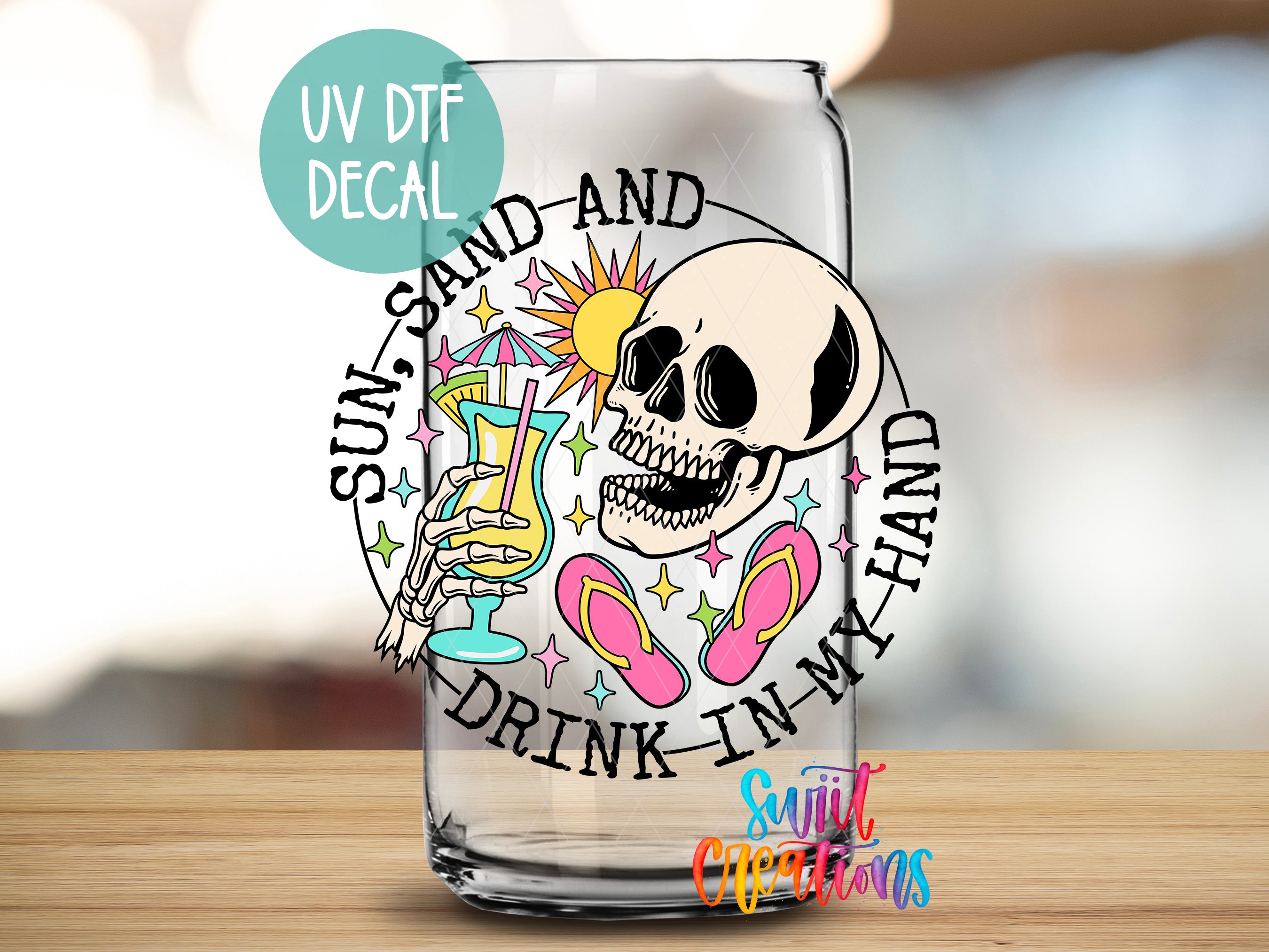 A glass with a skull and various beach-themed illustrations, including a sun, sand, and flip flops, along with the text "UV Dtf DECAL" and "SUN, SAND AND DRINK IN MY HAND".