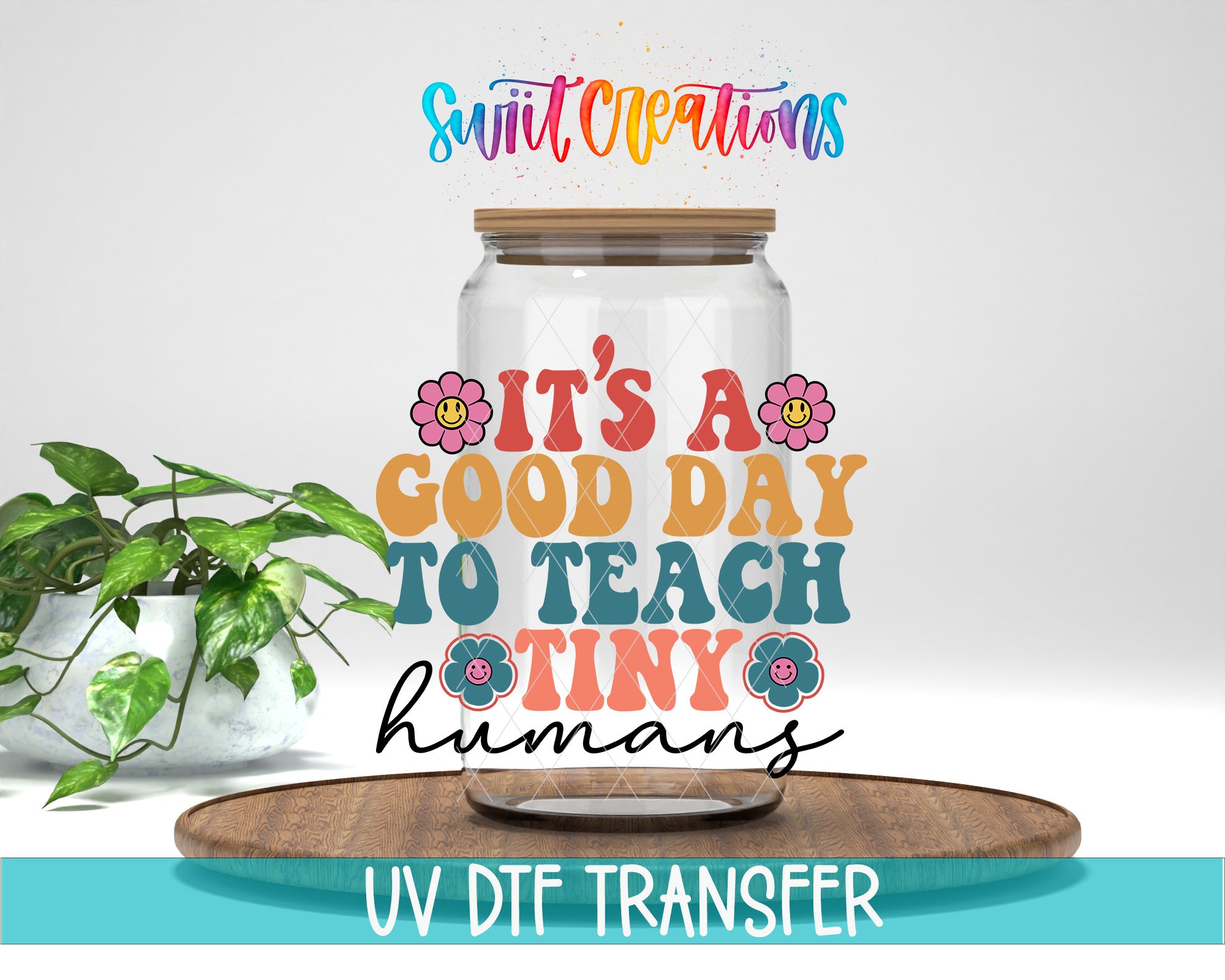 a clear glass jar with a wooden lid, surrounded by a potted plant and a wooden tray. The text on the jar reads "It's a good day to teach tiny humans" in a colorful, artistic style.