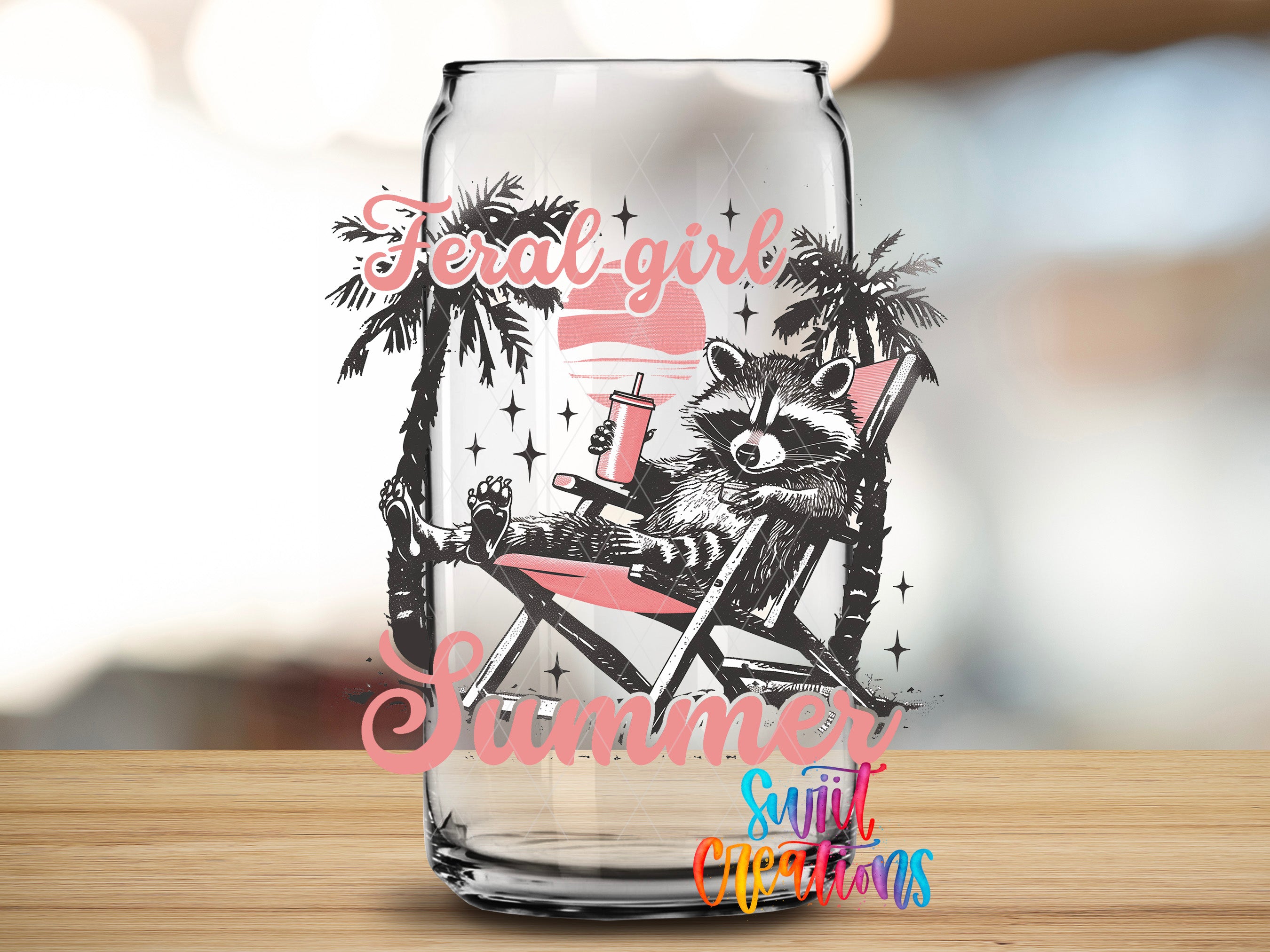 A glass can with a raccoon sitting in a beach chair, holding a drink, and surrounded by palm trees and stars, with the text "Feral Girl Summer" and "Sunlit Creations" printed on it.