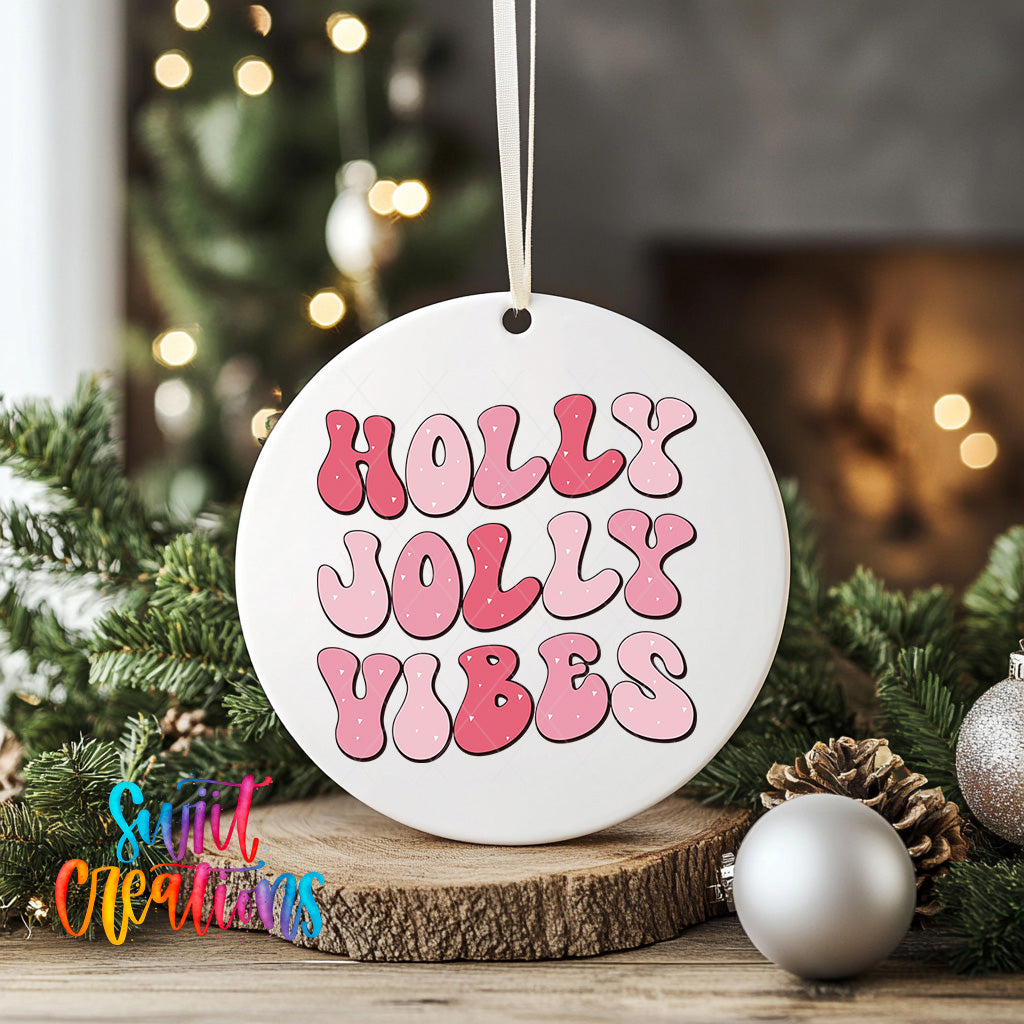 A white ornament with the text "Holly Vibes" in pink and red letters, hanging on a string. The ornament is surrounded by pine branches and other holiday decorations, creating a festive atmosphere.
