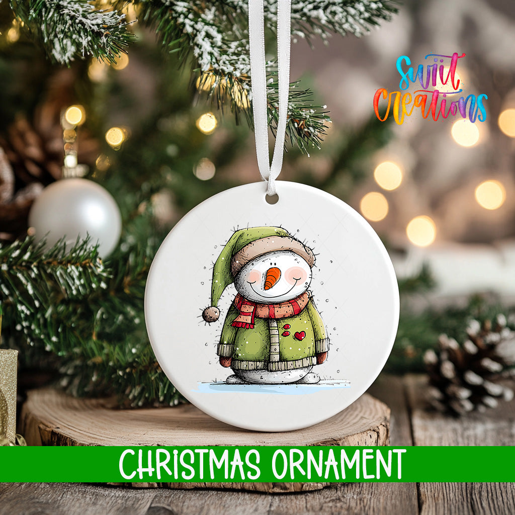 A white Christmas ornament featuring a snowman is hanging from a tree branch, with a blurred background of lights and pine cones.