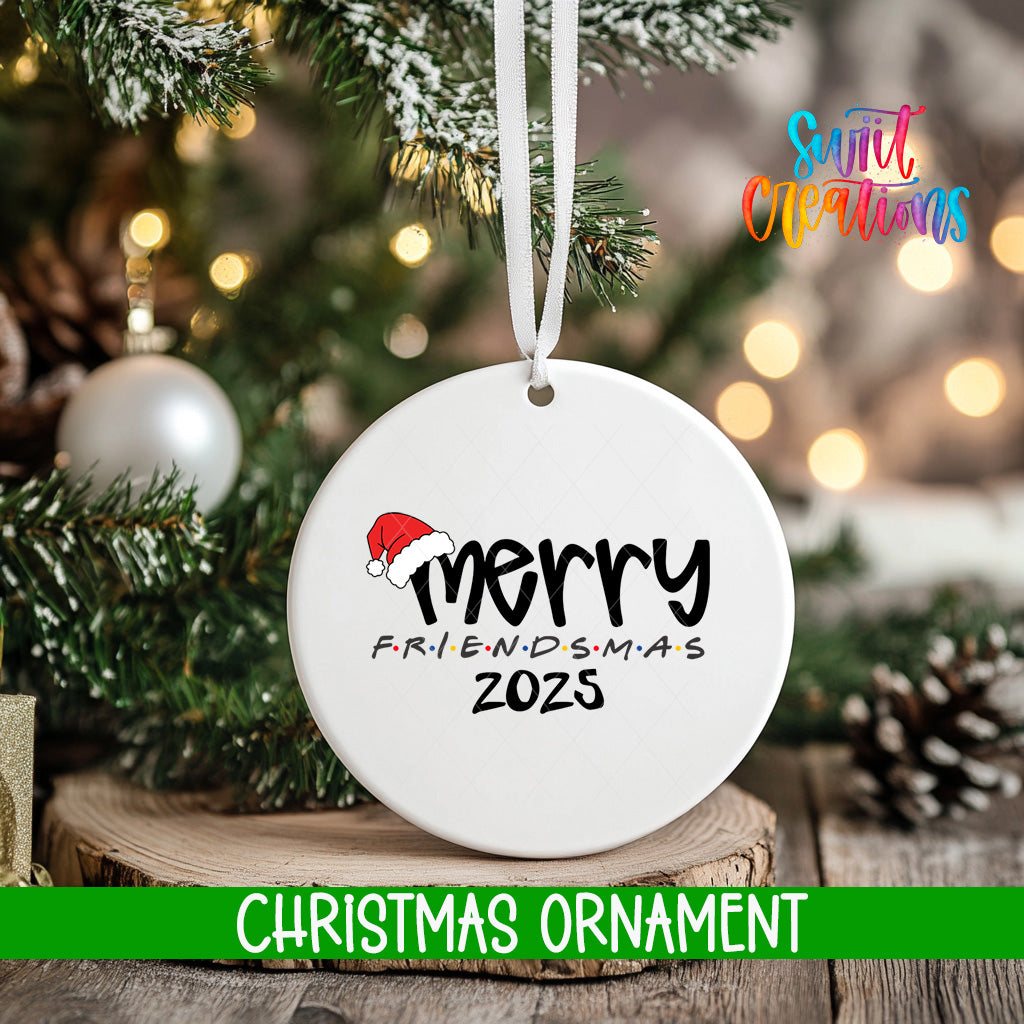 A white Christmas ornament with the text "Merry FRIENDSMAS 2025" hangs on a tree branch, surrounded by pine branches and twinkling lights.